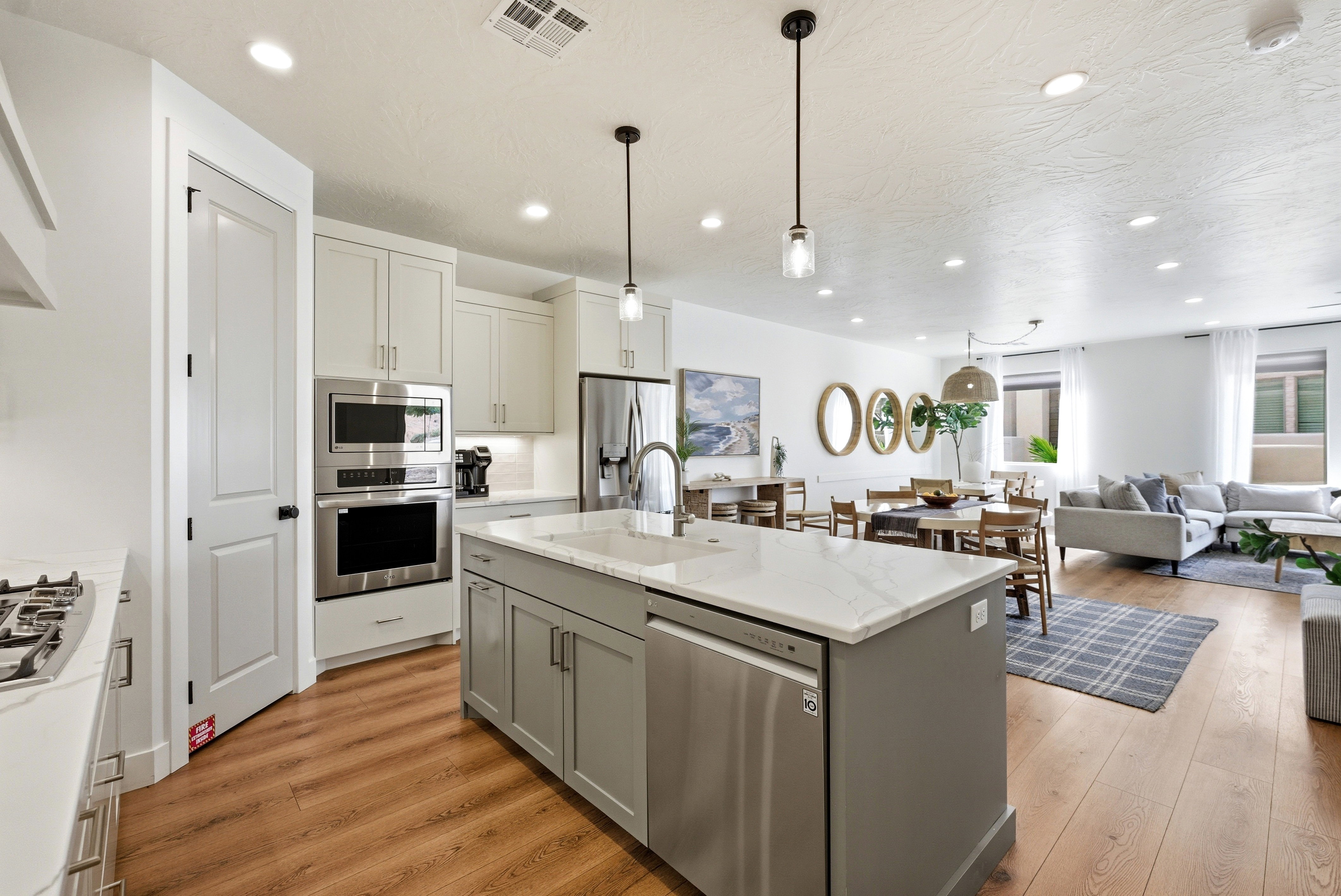 Open-concept living space featuring a kitchen with light cabinetry, stainless steel appliances, and a central island with a white countertop
