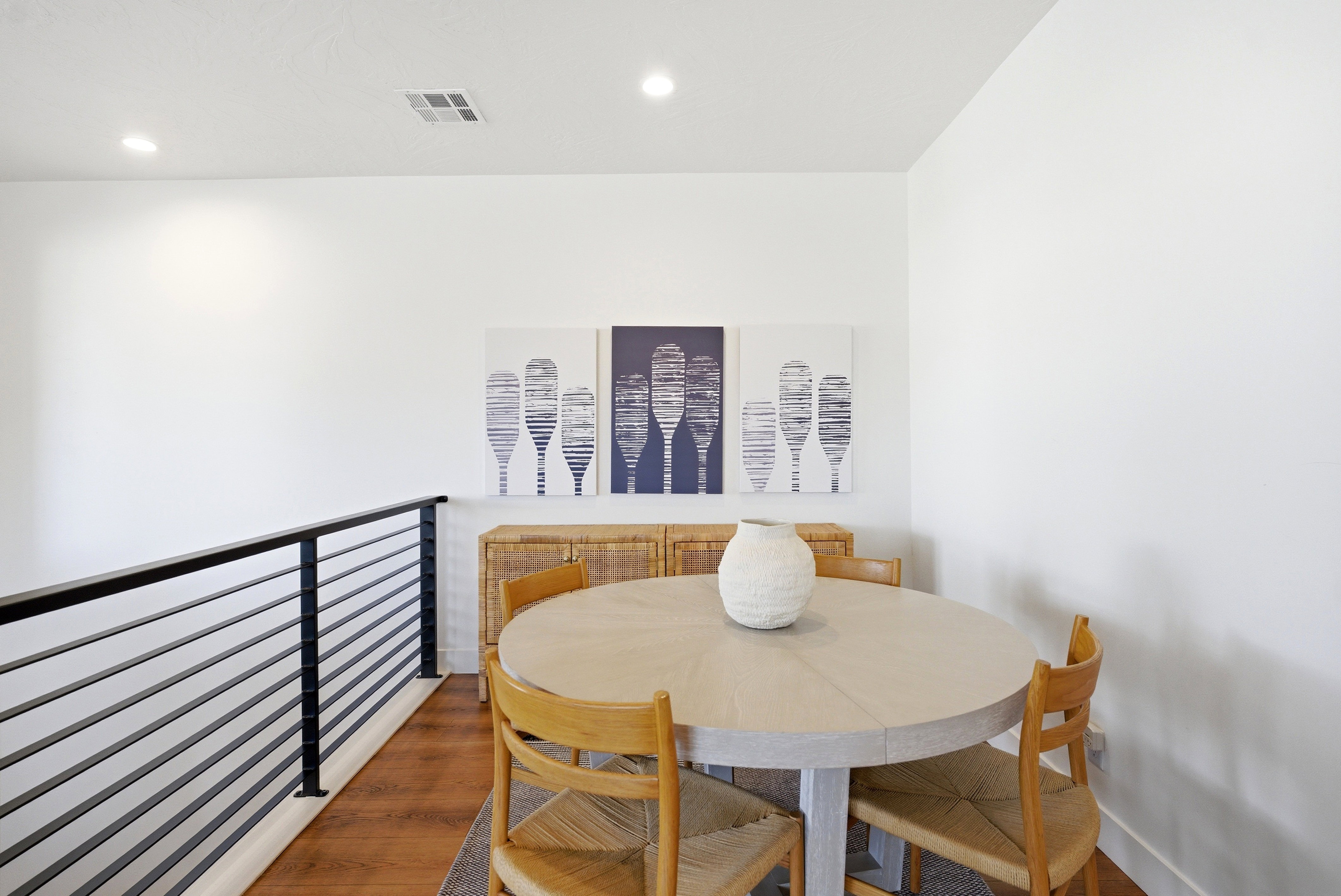 Upper-level interior space featuring a black horizontal bar railing system, wood-finish flooring, recessed lighting, and a white wall finish