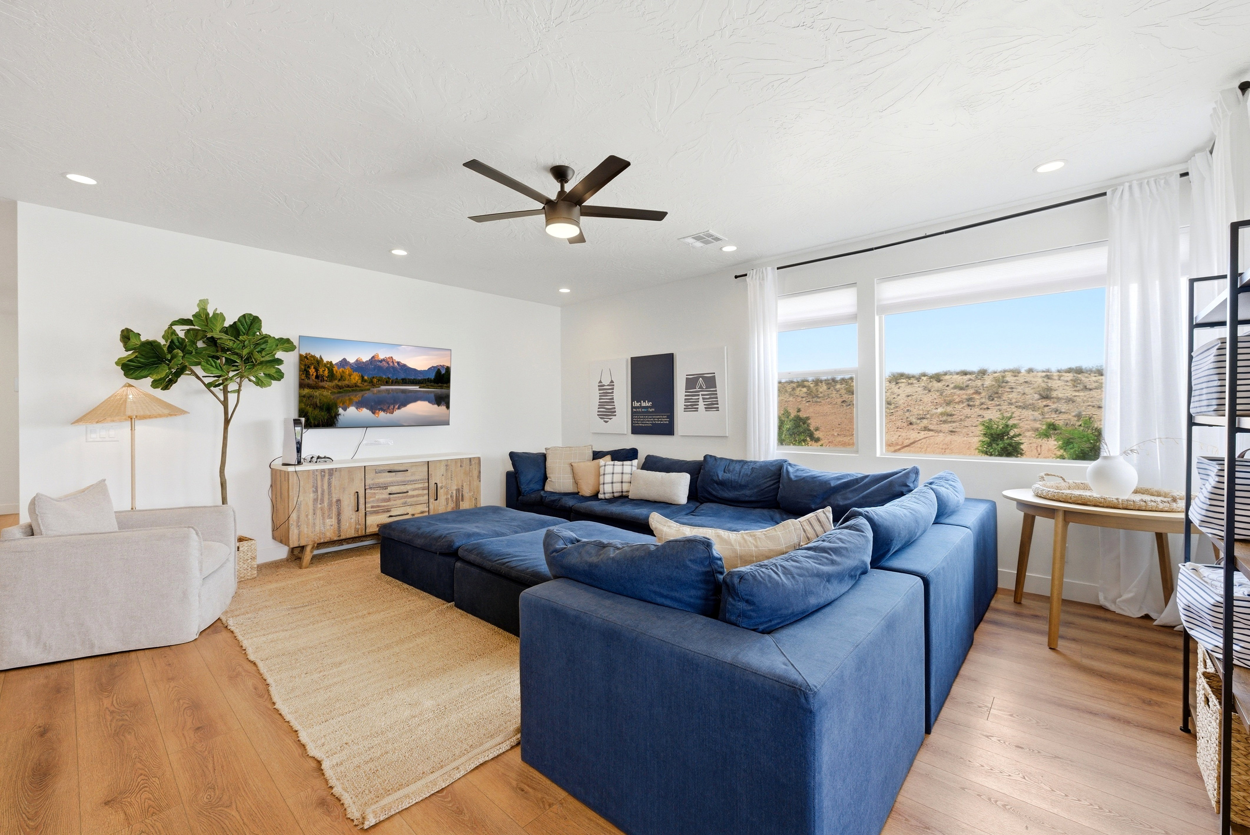 Spacious living area featuring light wood-finish flooring, recessed lighting, and a modern ceiling fan