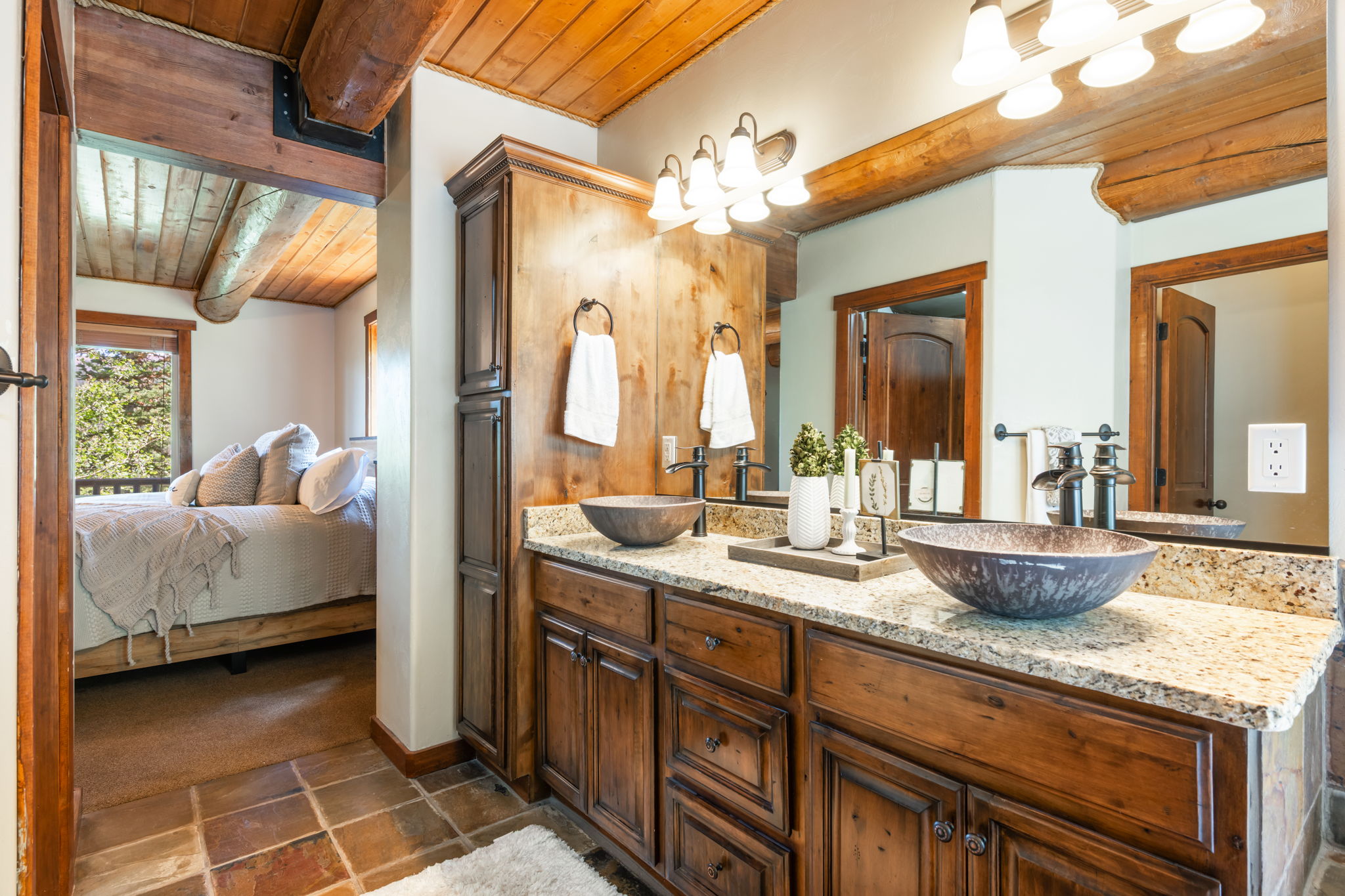 Double vanity featuring two vessel sinks with dark bronze fixtures, a speckled countertop, and wood cabinetry