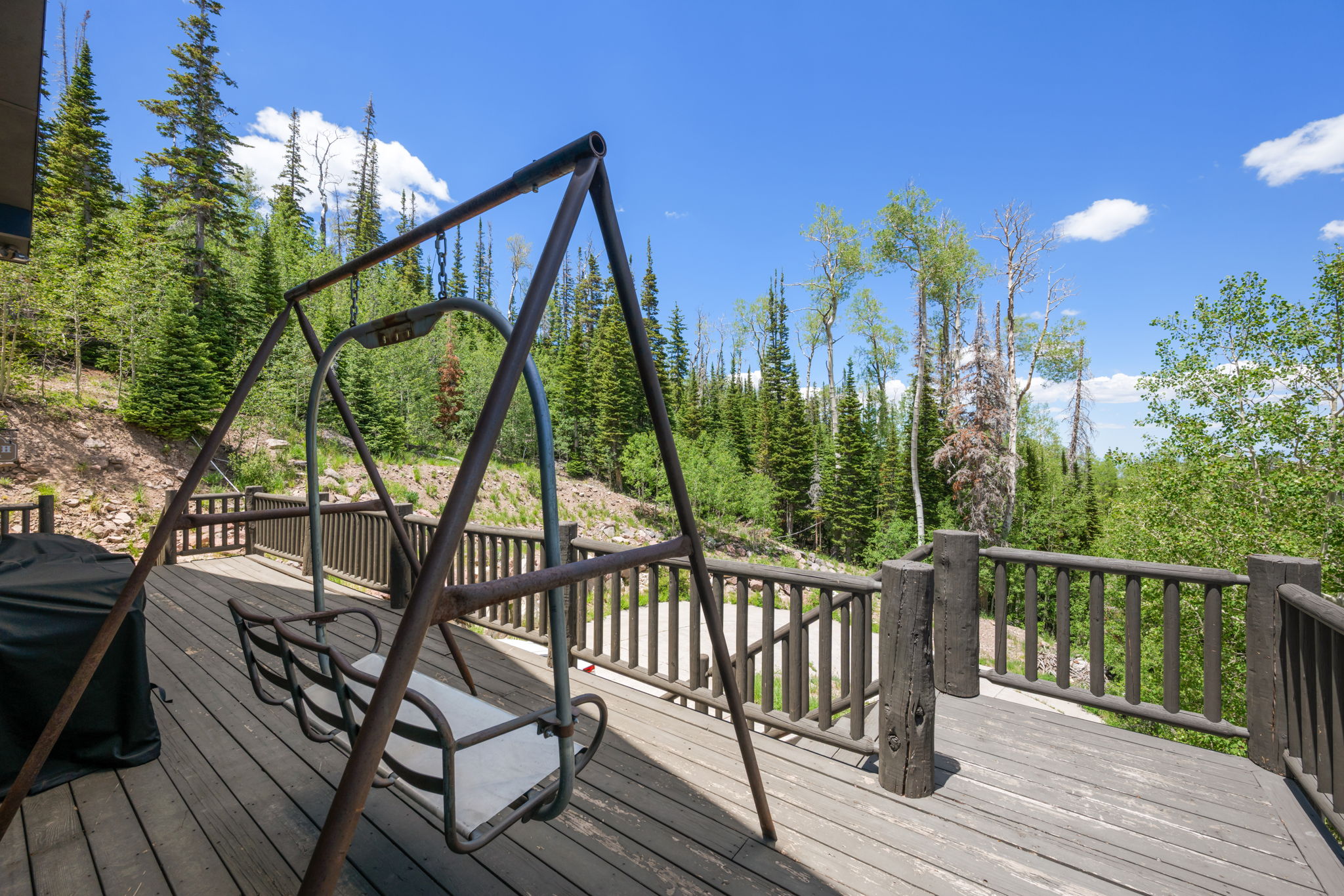 Expansive outdoor deck featuring wood-finish flooring and a rustic wood railing