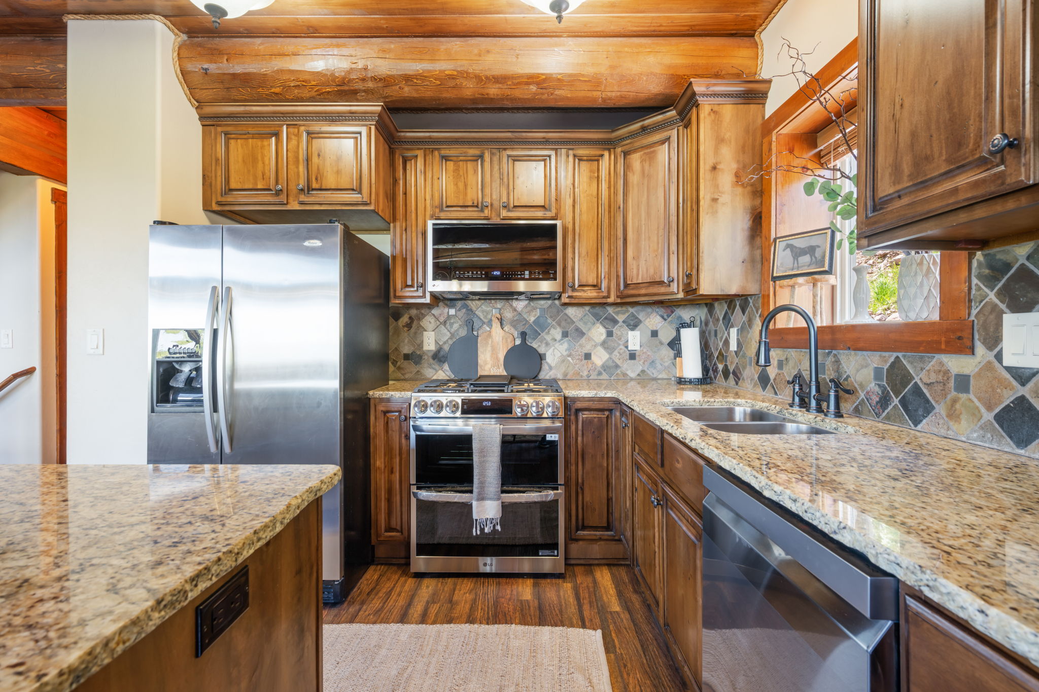 Kitchen featuring wood-finish cabinetry, granite countertops, stainless steel appliances, and a mosaic tile backsplash
