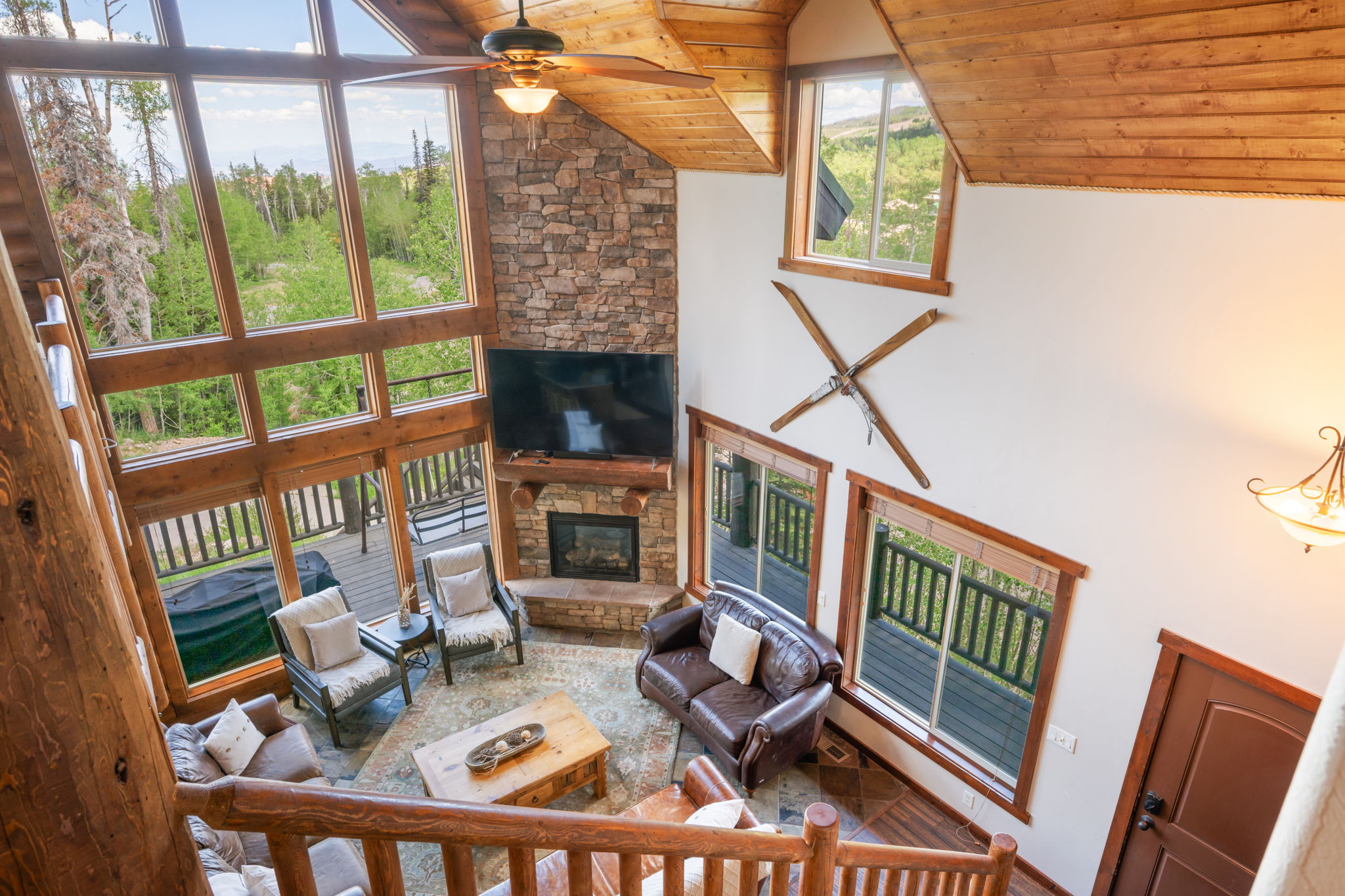 Two-story living area featuring a stone fireplace, wood-finish flooring, and a beamed wood ceiling