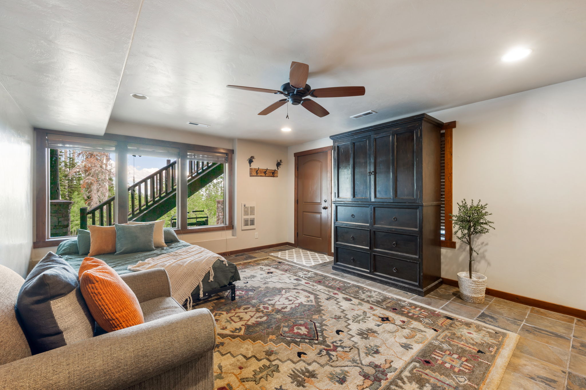 Bright room featuring multiple windows with dark wood frames, a wood-finish ceiling fan, and recessed lighting