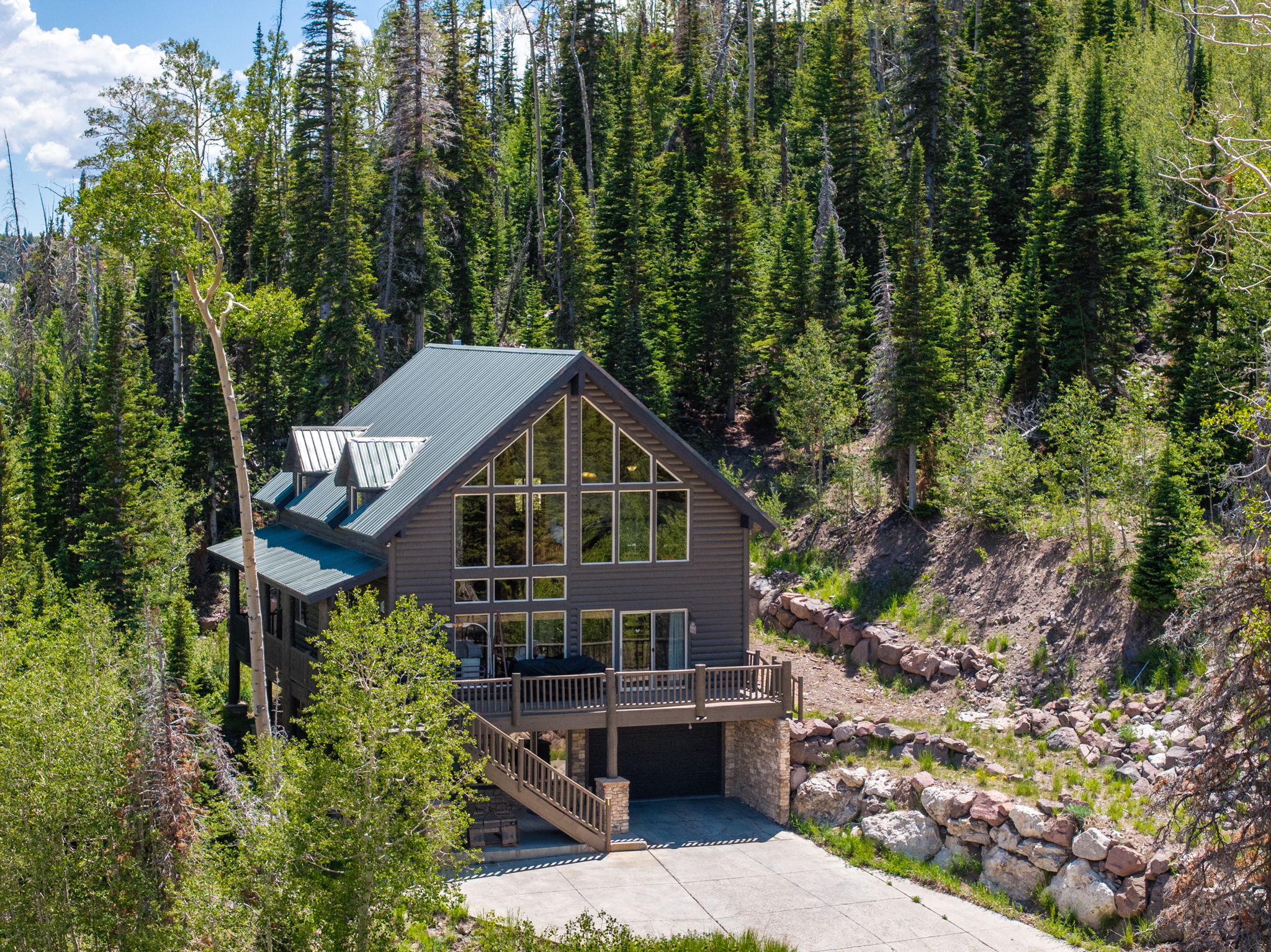 Mountain-style residence featuring a prominent wall of windows, dark gray siding, and a metal roof