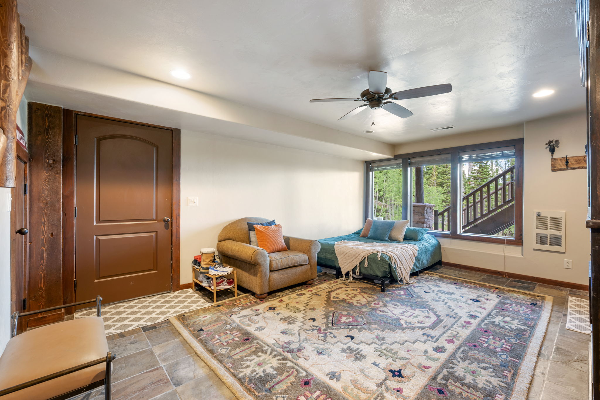 Natural light-filled room featuring large windows, slate flooring, and a ceiling fan