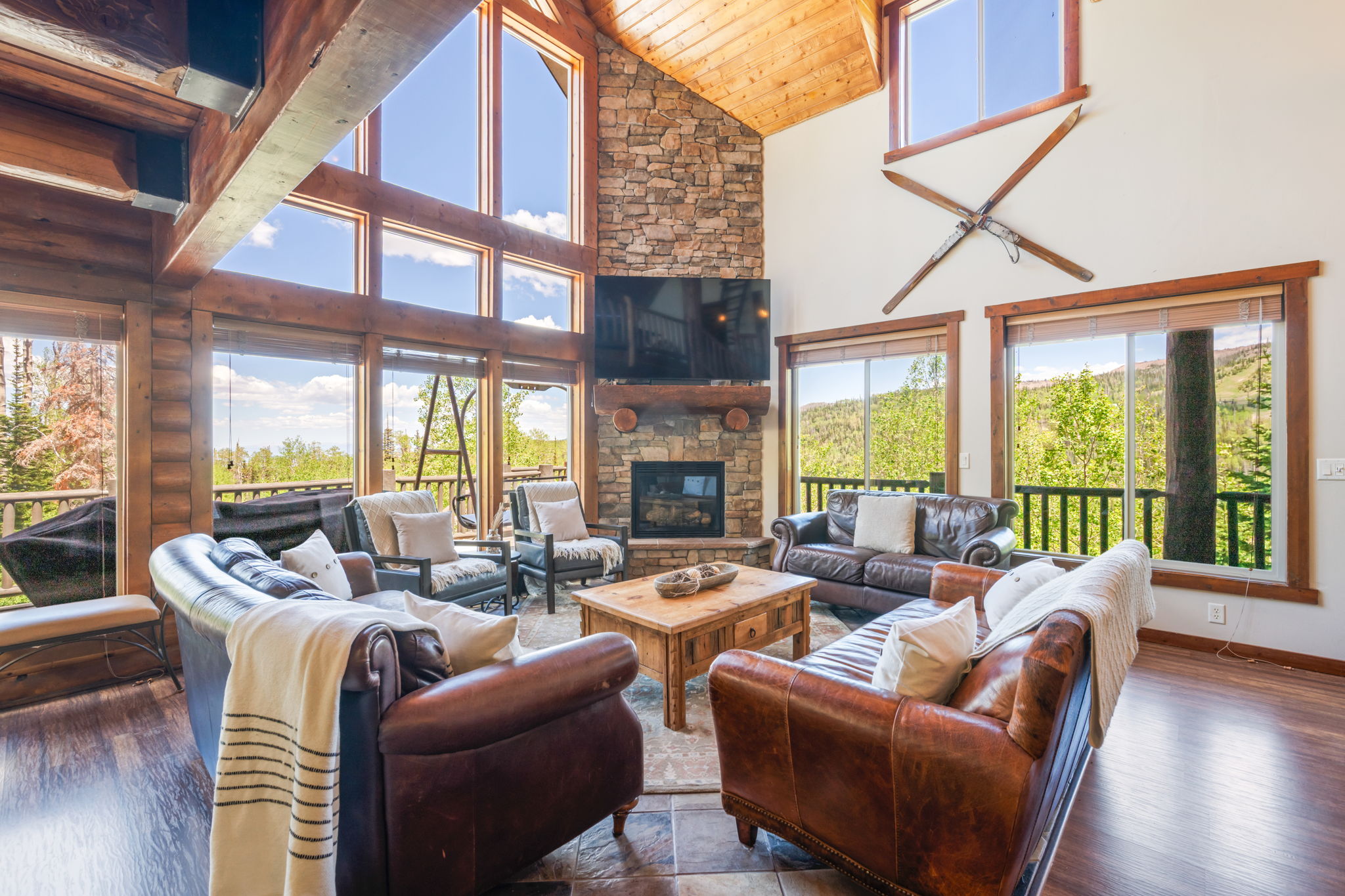 Vaulted living space featuring a stone-clad fireplace and wood-finish flooring