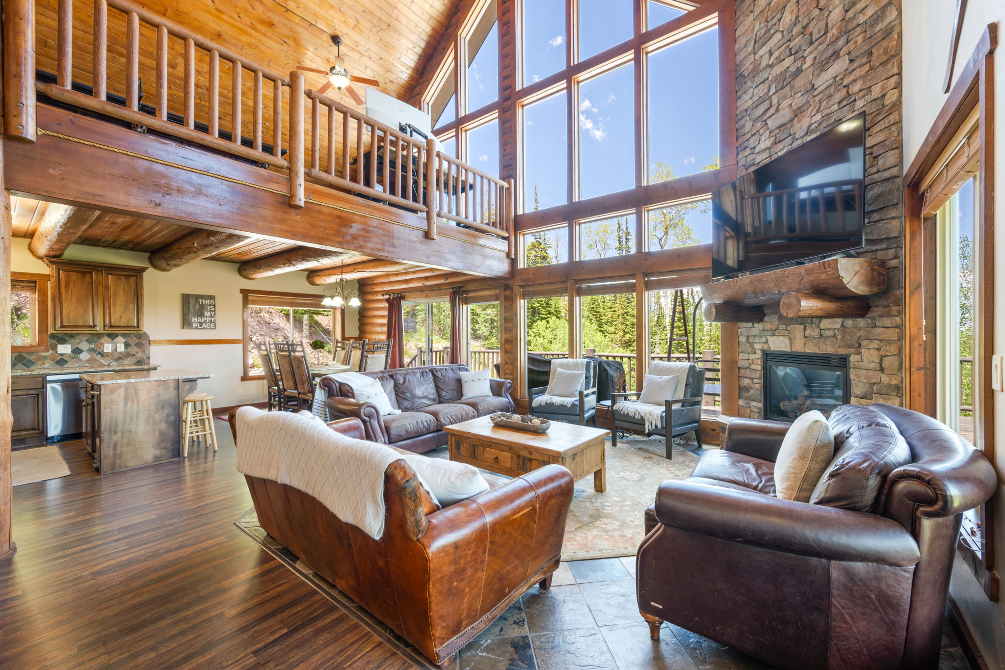 Great room featuring a natural stone fireplace, floor-to-ceiling windows, wood-finish flooring, and a lofted ceiling with exposed wood beams