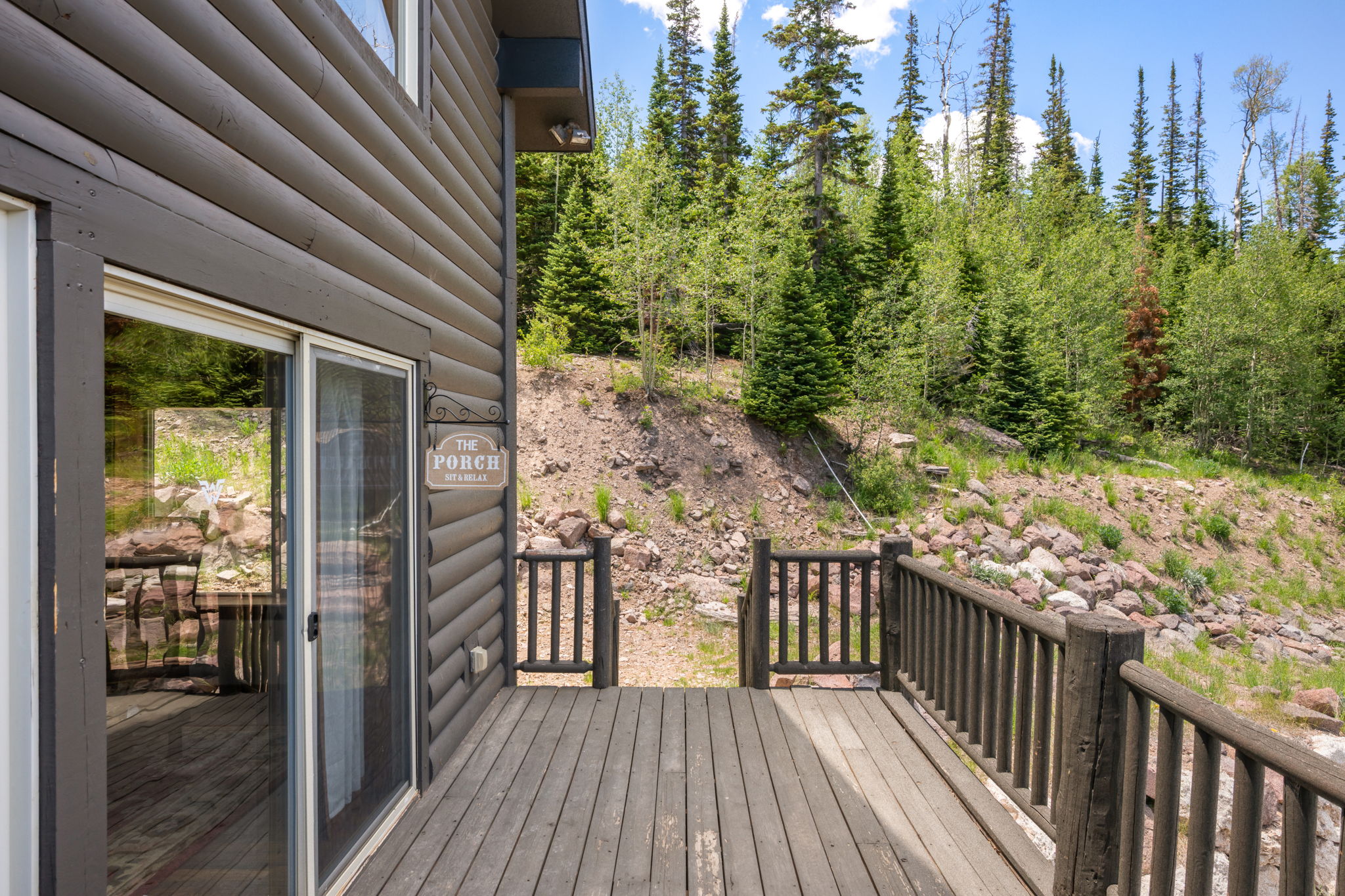 Wood-finish exterior with a sliding glass door opening to a spacious deck