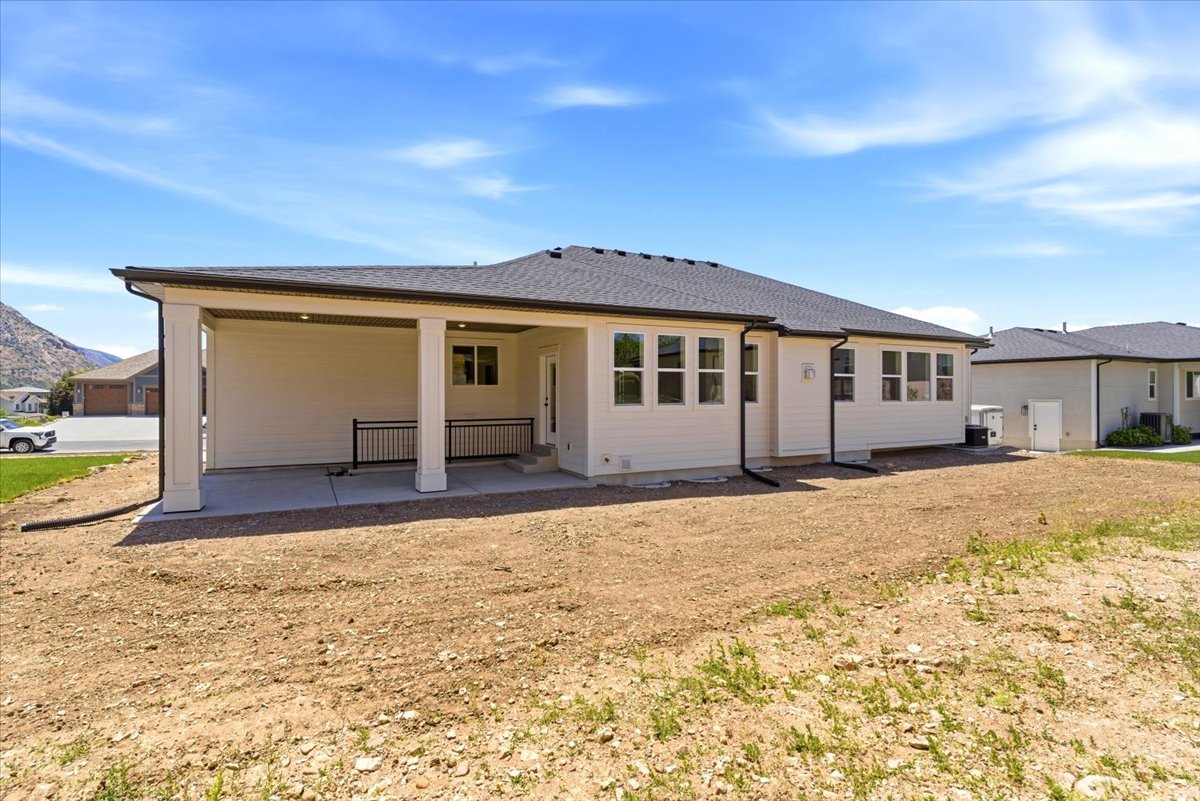 Expansive rear exterior featuring a covered patio with a concrete surface, walk-out from basement and black metal railing