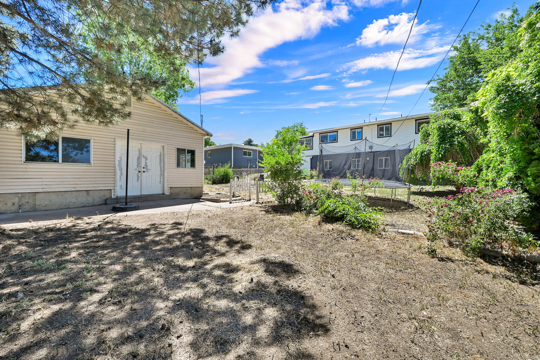 Spacious backyard featuring a detached outbuilding with vinyl siding, a concrete foundation, and double entry doors