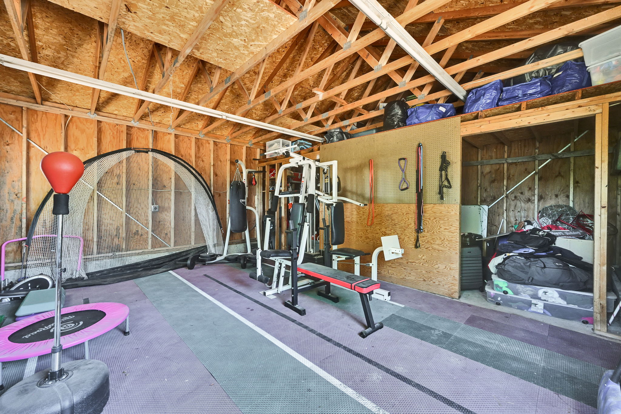 Open-concept attic space featuring exposed wood beam ceilings and wood-paneled walls