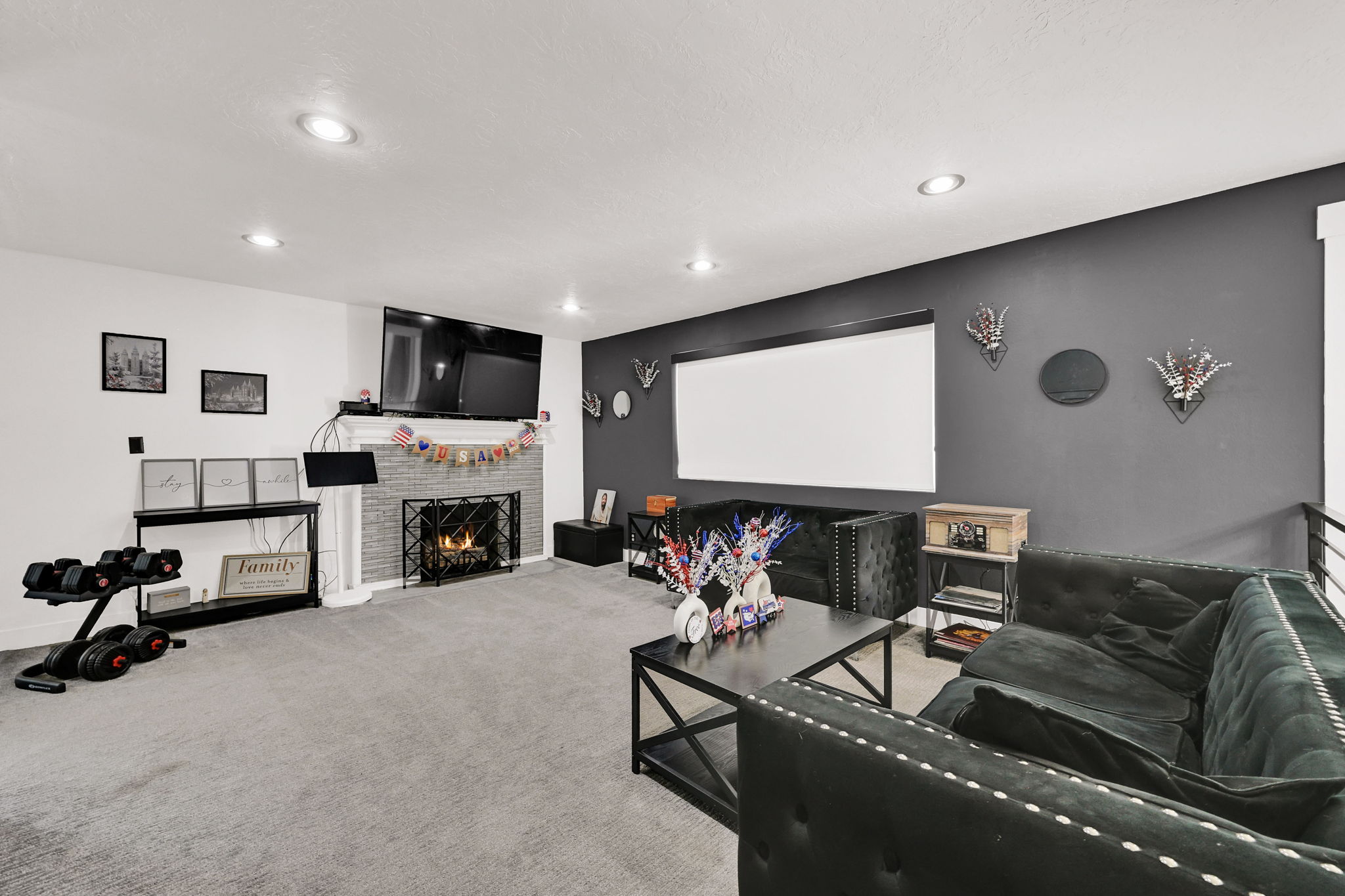 Spacious living area featuring a fireplace with a stone surround, a projection screen, recessed lighting, and soft carpet flooring