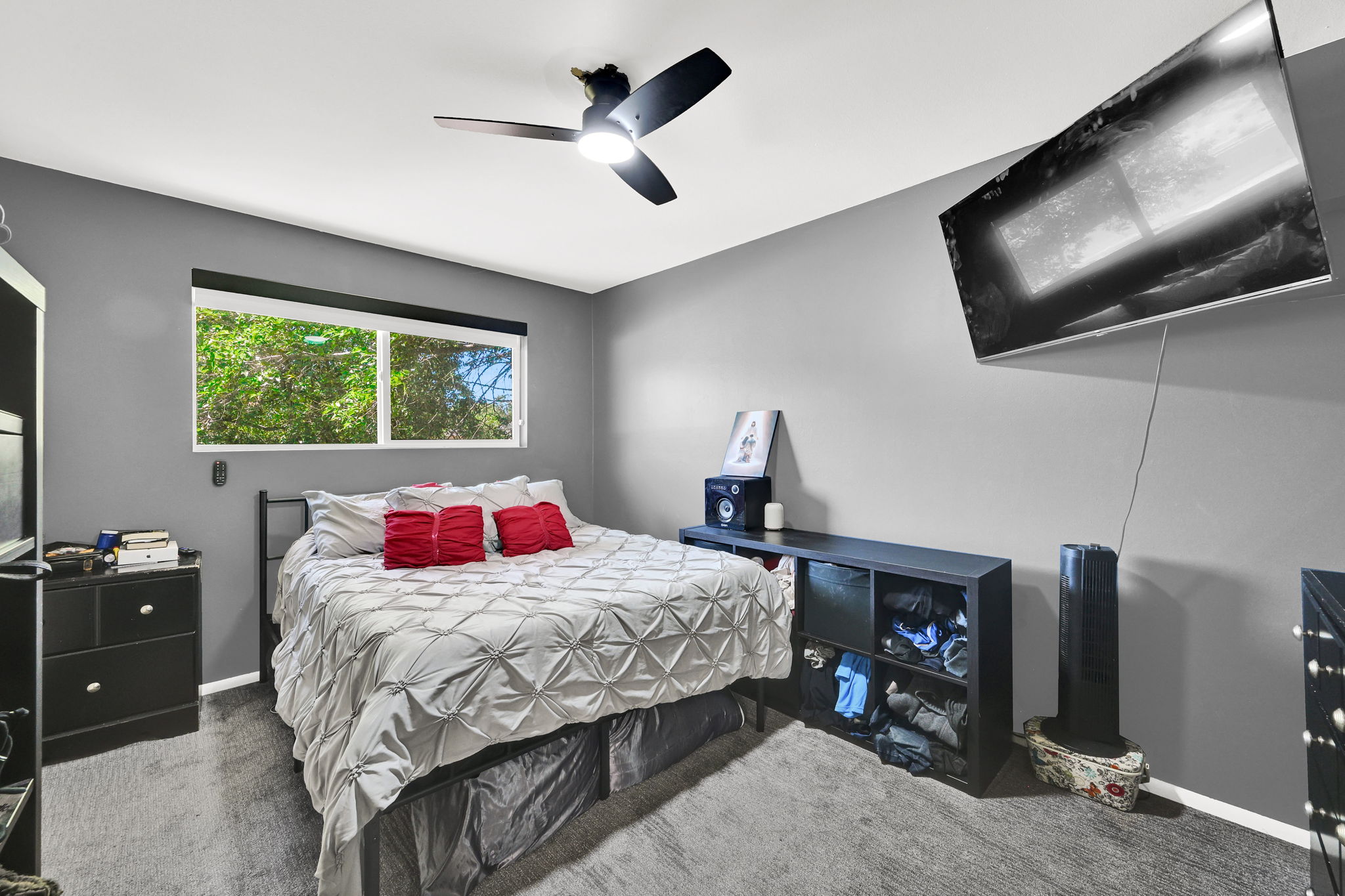 Bedroom featuring a ceiling fan with integrated lighting, wood-finish flooring, and a large window with natural light