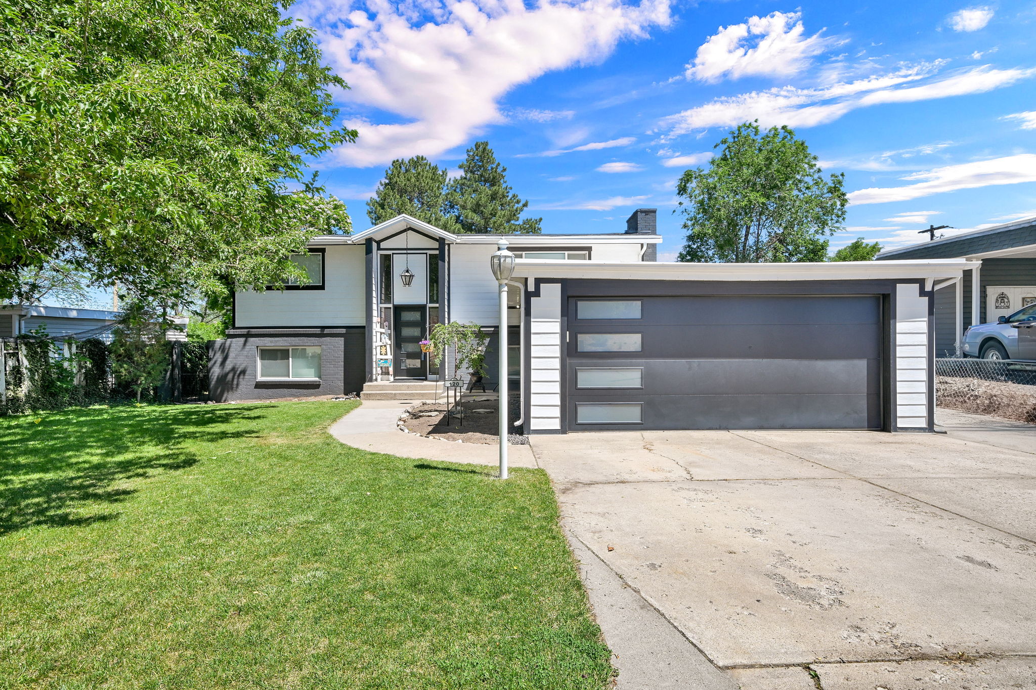 Modern exterior featuring a prominent black garage door with frosted window panels, white siding, and a contrasting black brick lower level