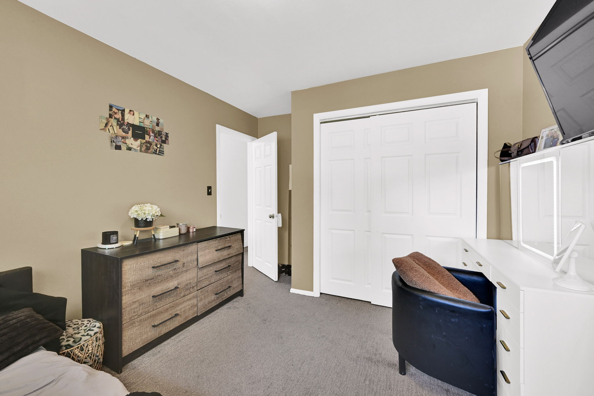 Carpeted room featuring a white paneled bi-fold closet, neutral wall paint, and white trim