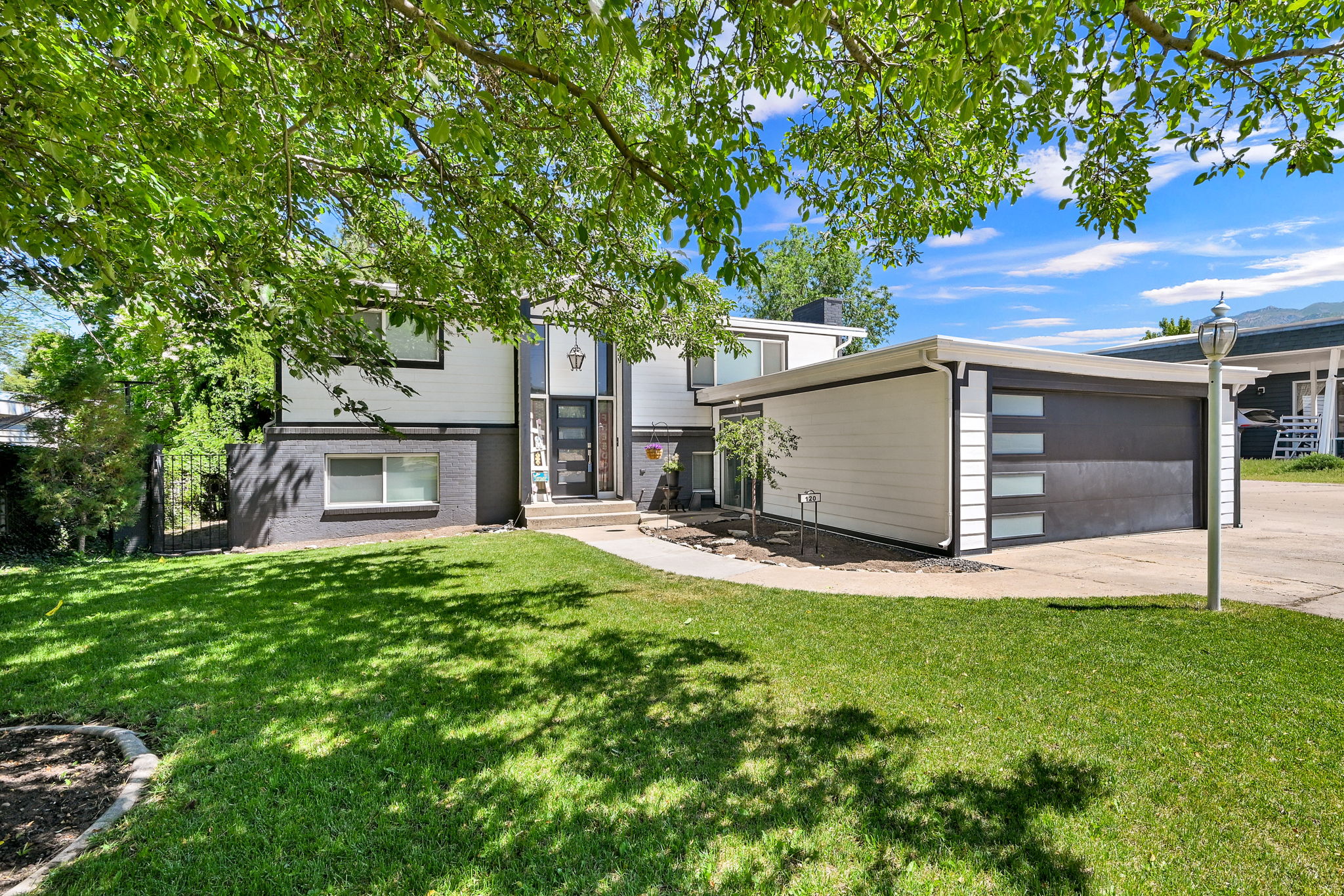 Contemporary facade with contrasting dark and white siding, a modern garage door with frosted panels, and a concrete driveway