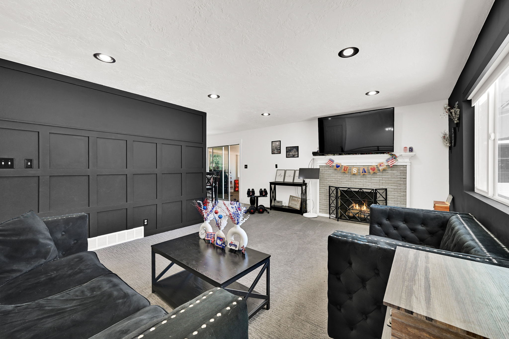 Spacious living area featuring a board and batten accent wall, recessed ceiling lighting, and light grey carpeting