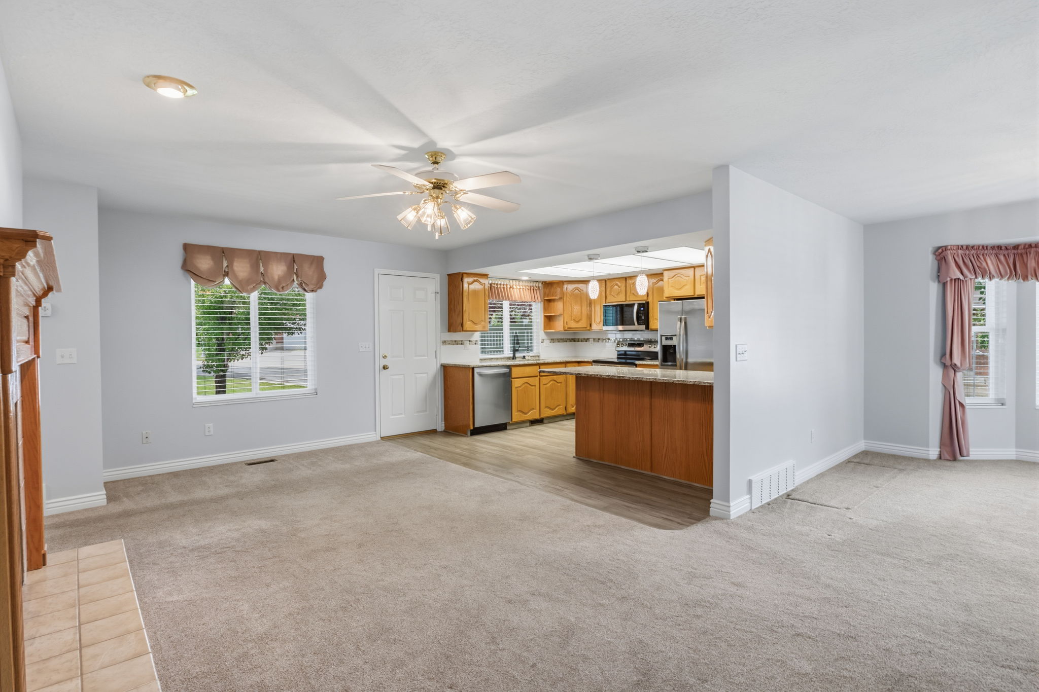 Open-concept living area featuring a neutral carpet, a ceiling fan with integrated lighting, and recessed ceiling lights