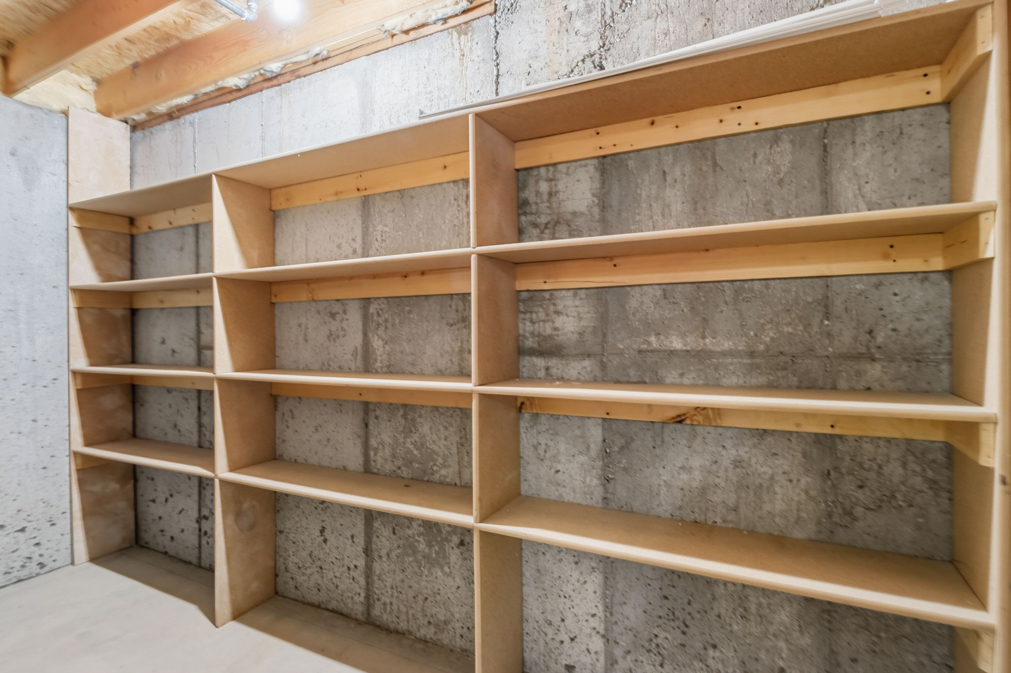 Built-in wood shelving units against concrete walls, featuring multiple tiers and divisions for comprehensive organization