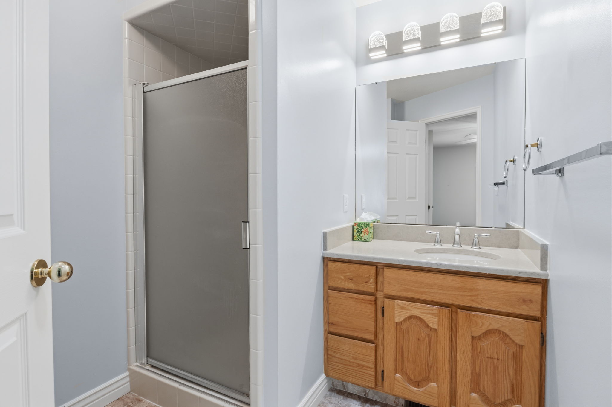 Bathroom featuring a single vanity with wood cabinetry, a light-toned countertop, and an integrated sink