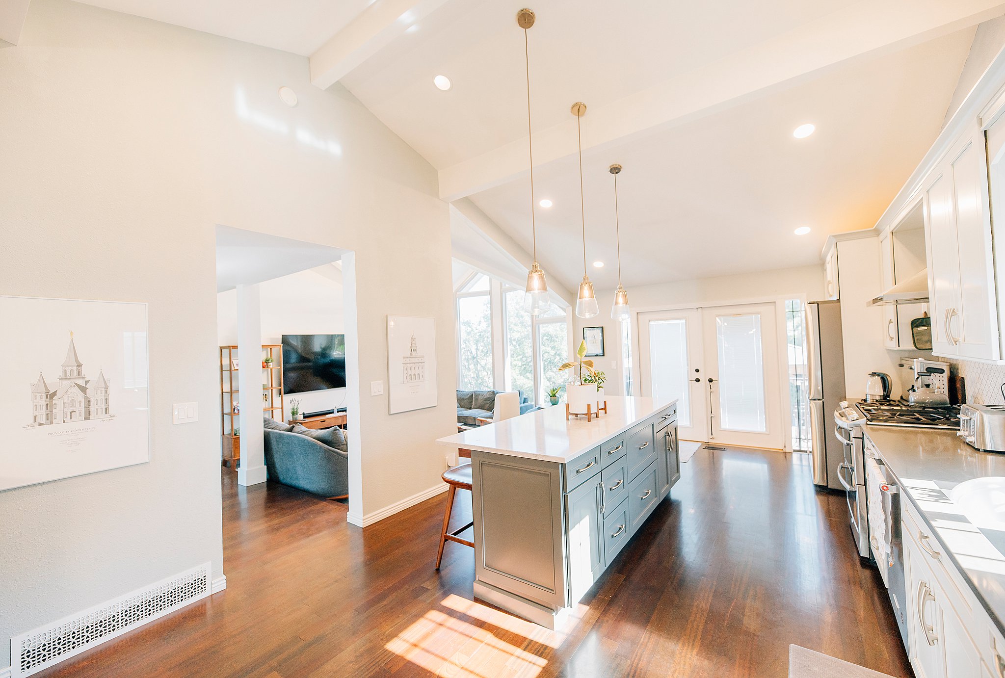 Kitchen featuring a center island with pendant lighting, white upper and gray lower cabinetry, stainless steel appliances, and wood-finish flooring