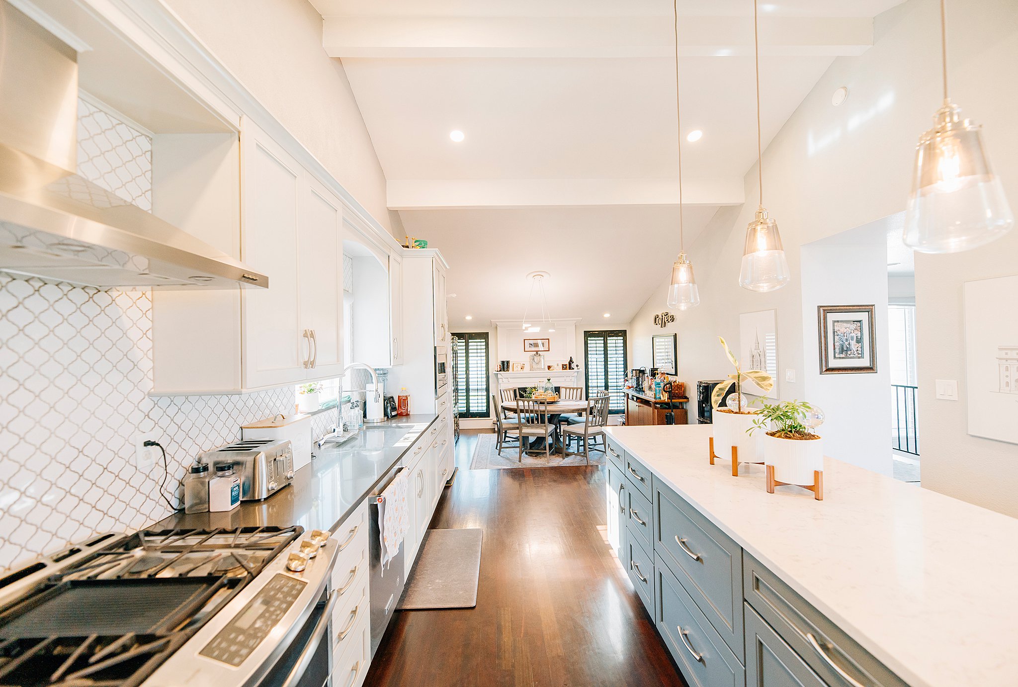 Kitchen featuring an expansive center island, pendant lighting, recessed lighting, wood-finish flooring, and white cabinetry with gold-tone hardware