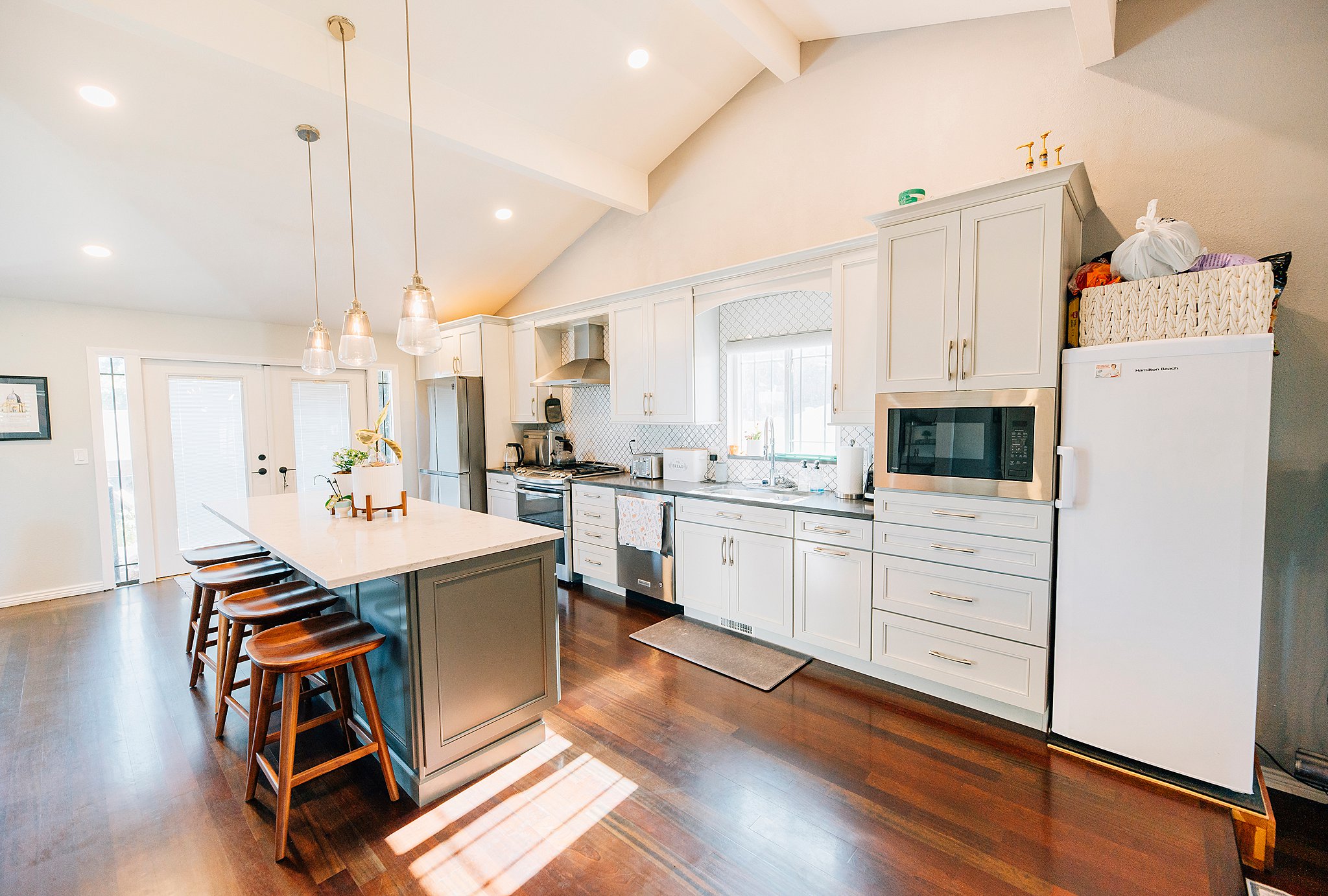 Spacious kitchen featuring a large central island with seating, a vaulted ceiling, recessed lighting, and rich wood-finish flooring