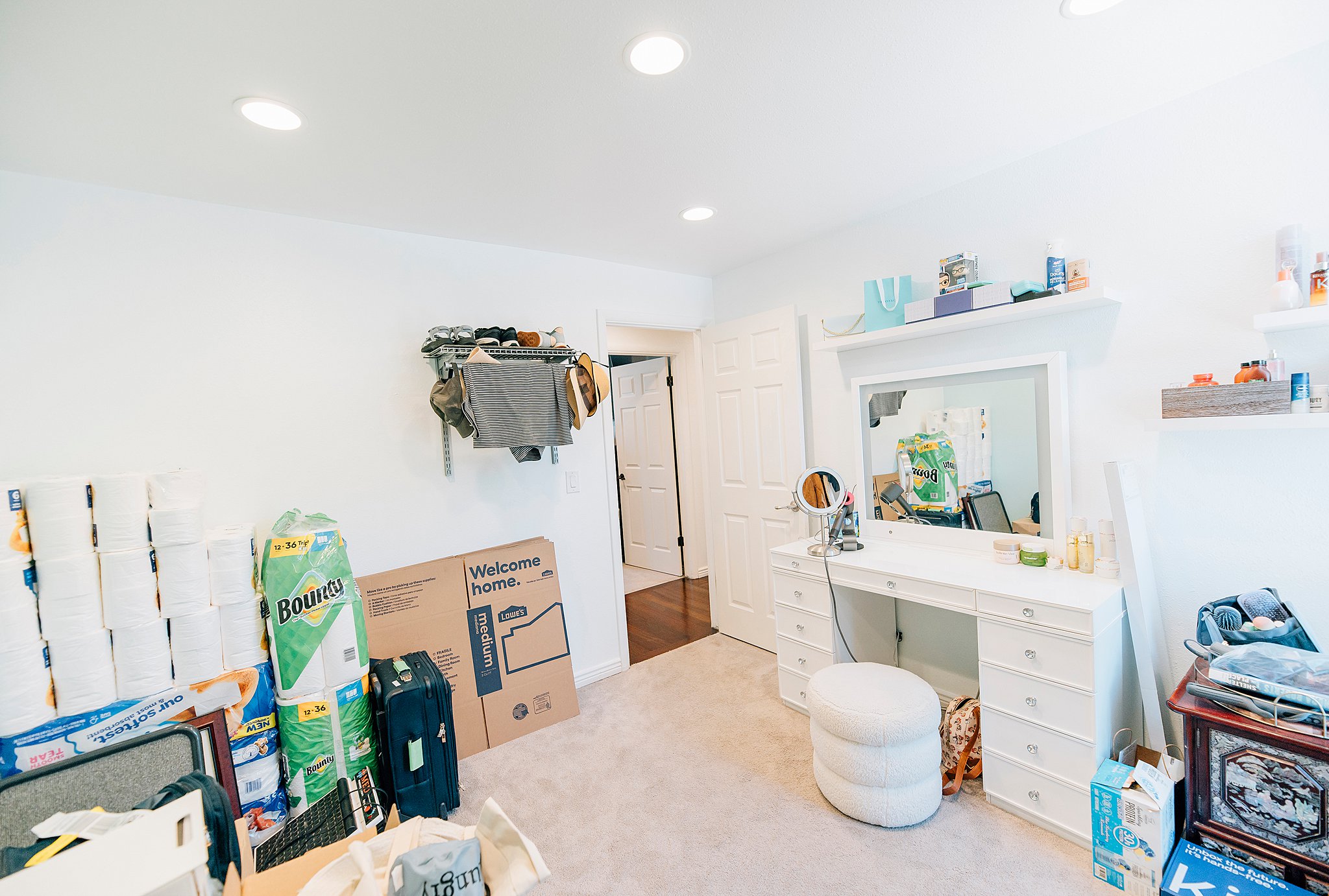 Recessed lighting illuminates a carpeted room featuring a built-in wall shelf and a white paneled door