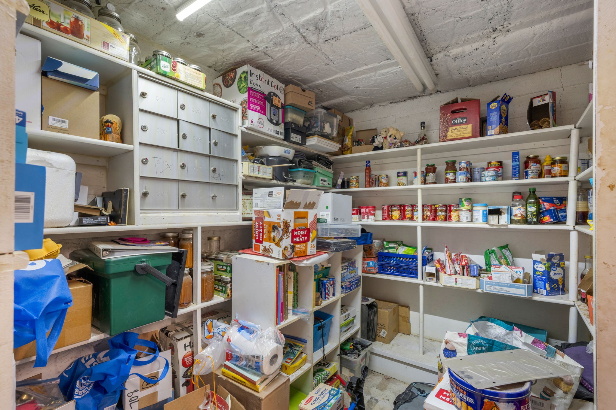 Storage room featuring white built-in shelving, fluorescent lighting, and a textured ceiling