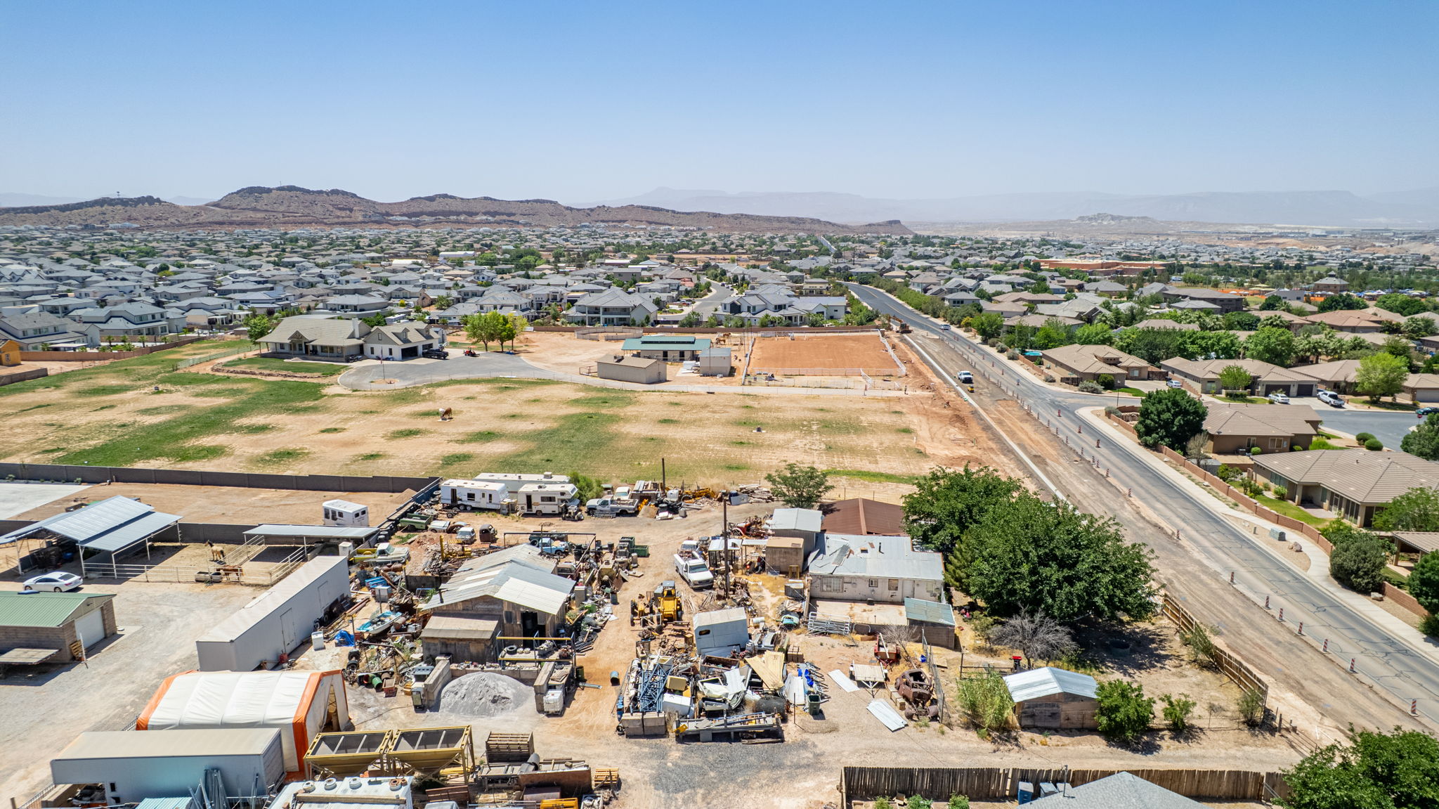 Expansive land parcel with surrounding residential development and distant mountainous terrain