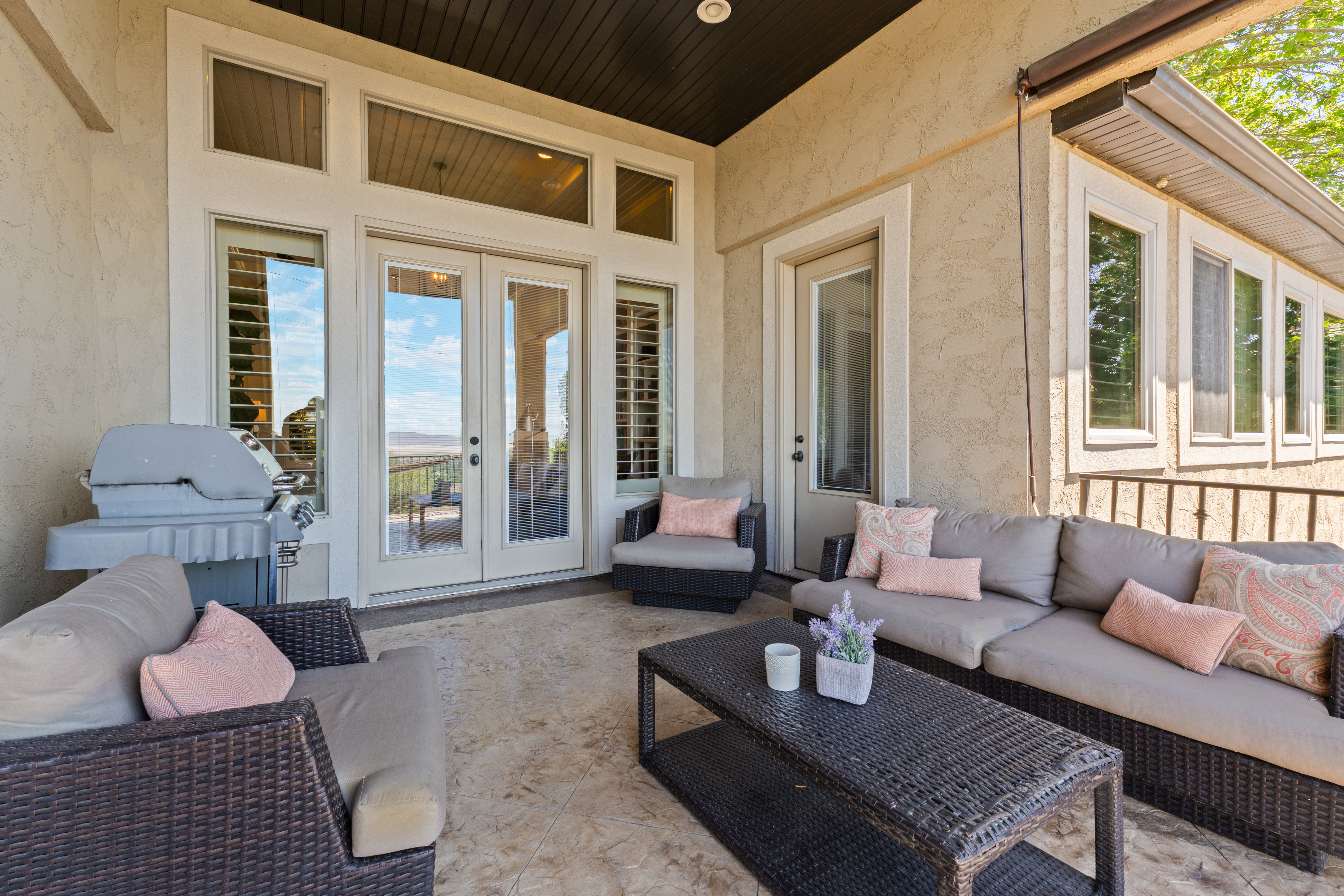 Expansive covered patio featuring stucco exterior, multiple glass-paned doors, and large transom windows