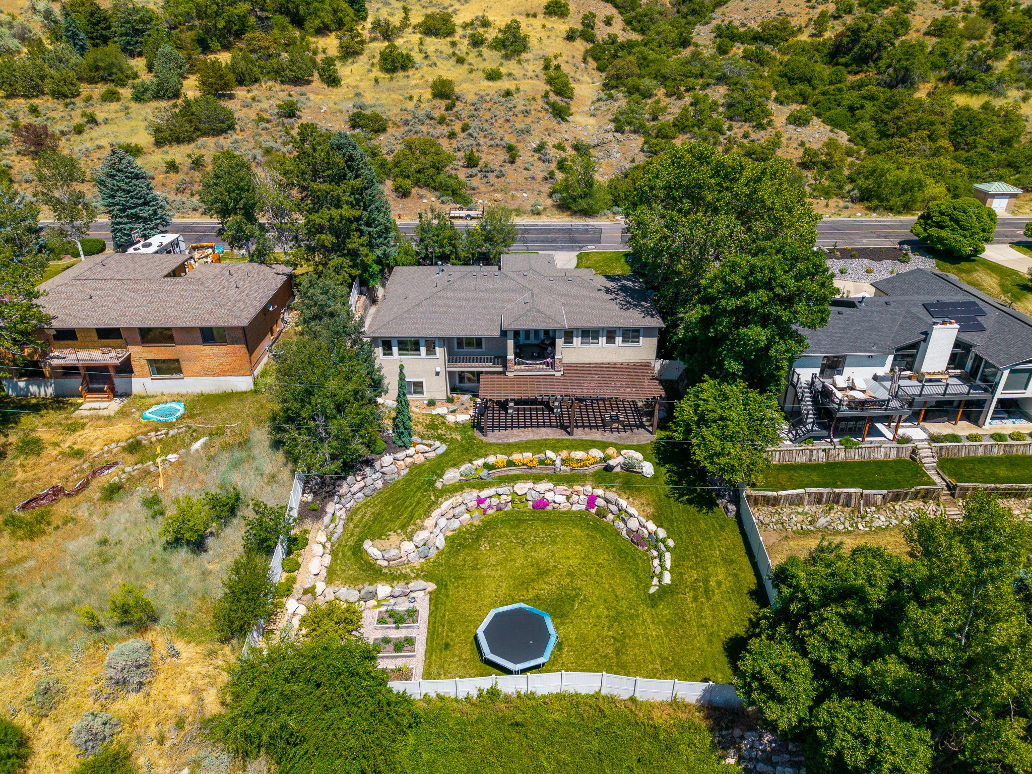 Expansive backyard featuring a lush lawn, terraced landscaping with natural rock elements, and raised garden beds