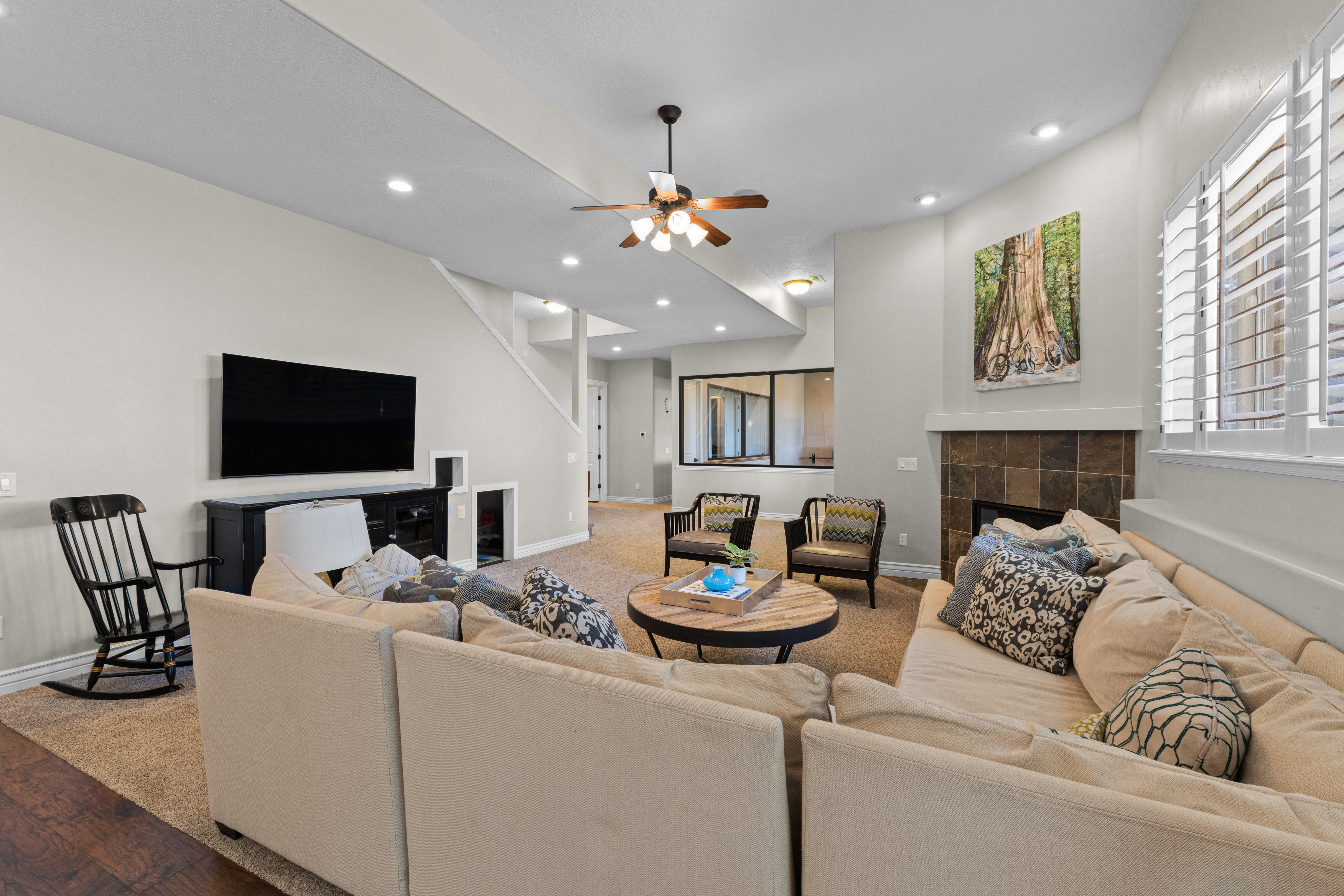 Living area featuring a stone tile fireplace, white plantation shutters, recessed lighting, and a ceiling fan