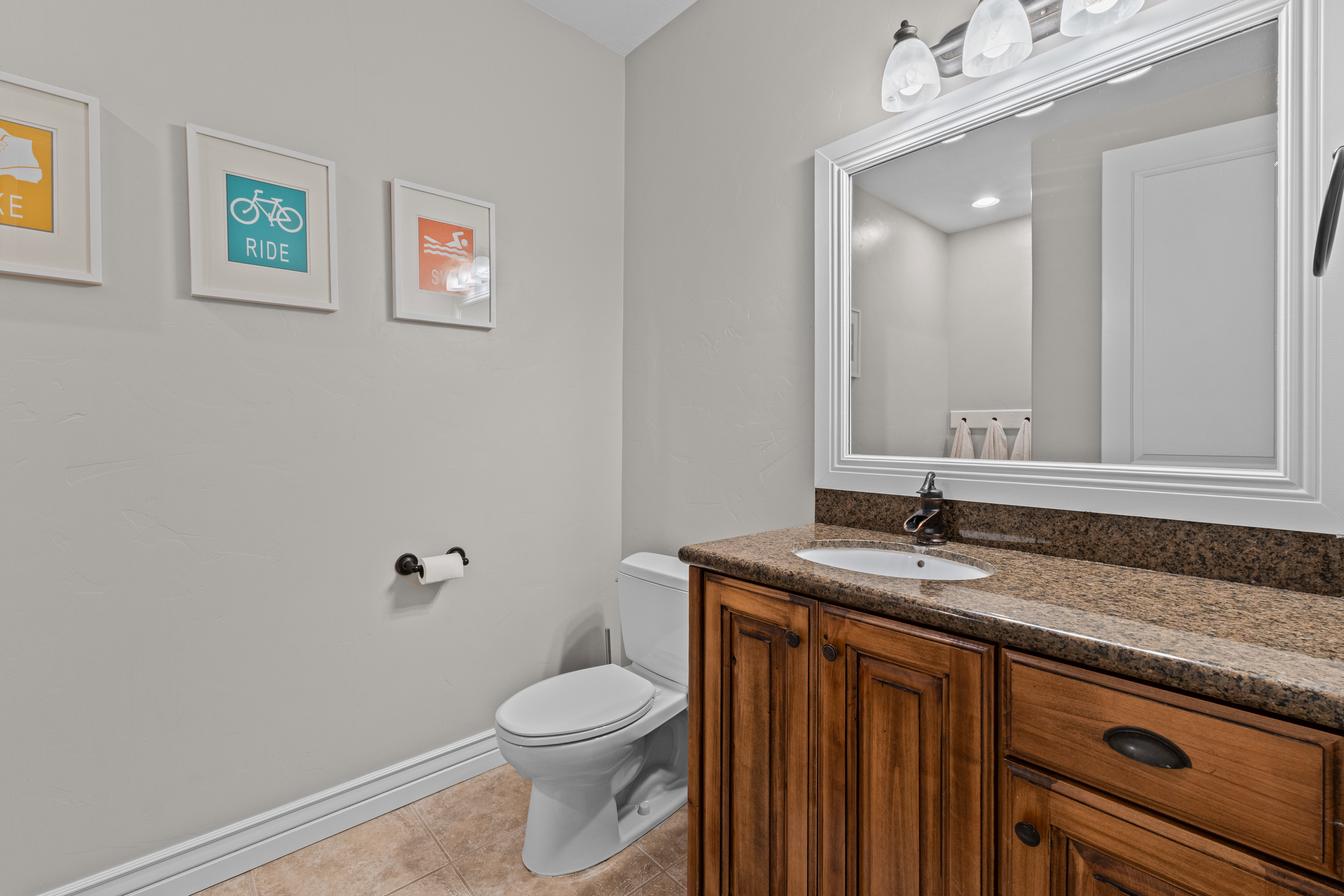 Bathroom featuring a wood-finish vanity with a built-in sink, stone countertop, and a framed mirror
