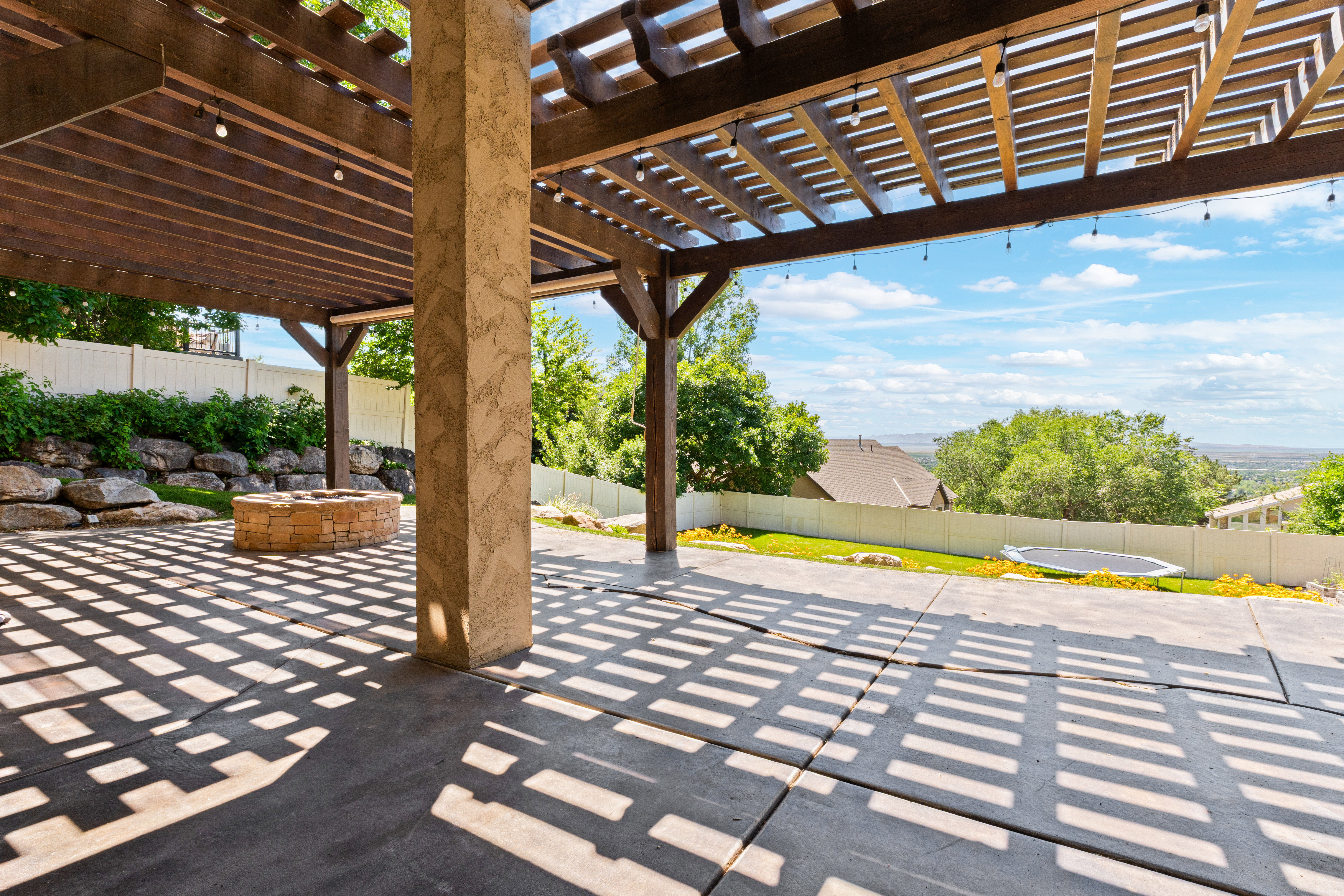 Expansive covered patio featuring a wood pergola and string lighting