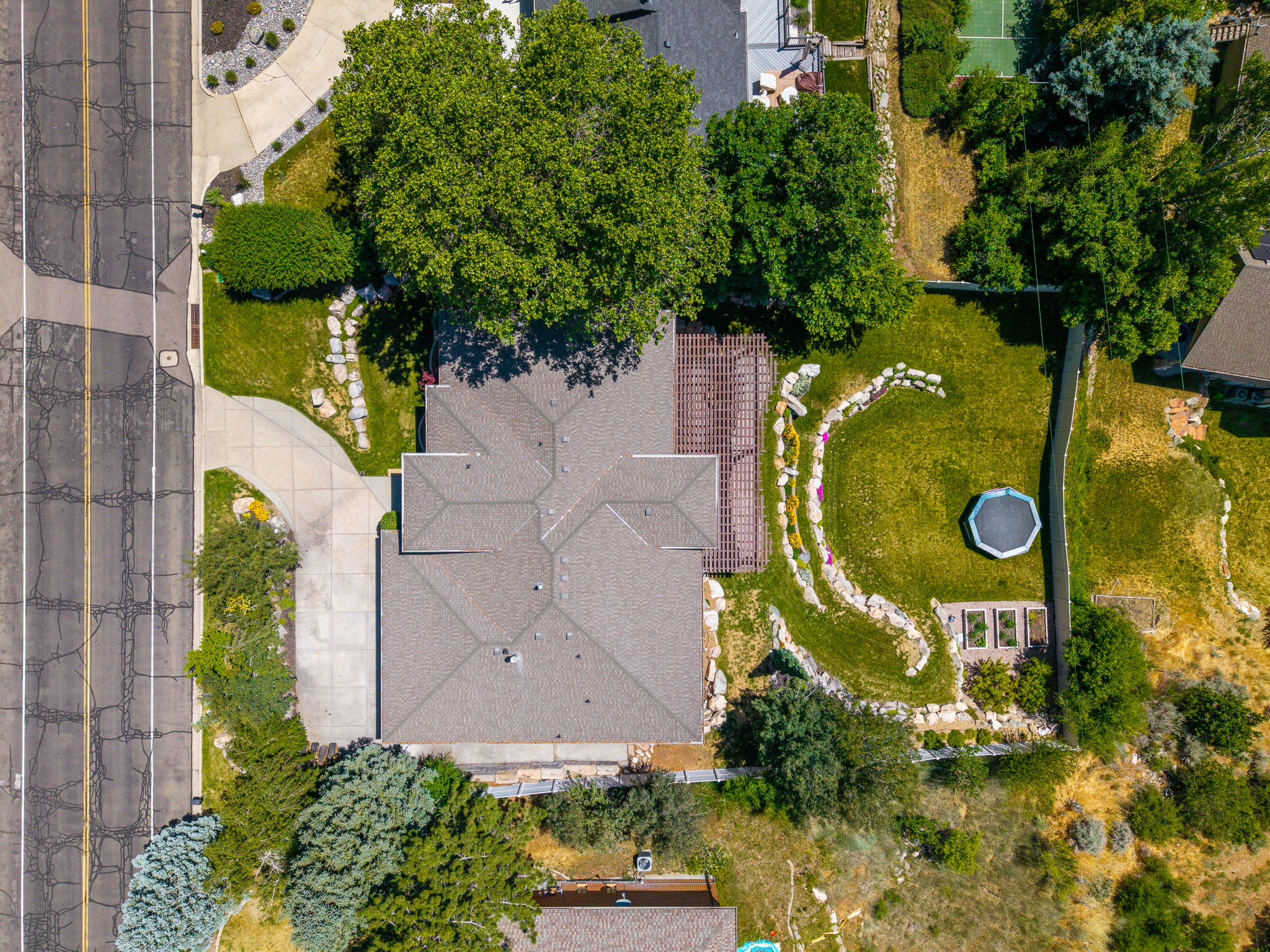 Expansive rear yard featuring a large lawn area, decorative rock landscaping, and raised garden beds