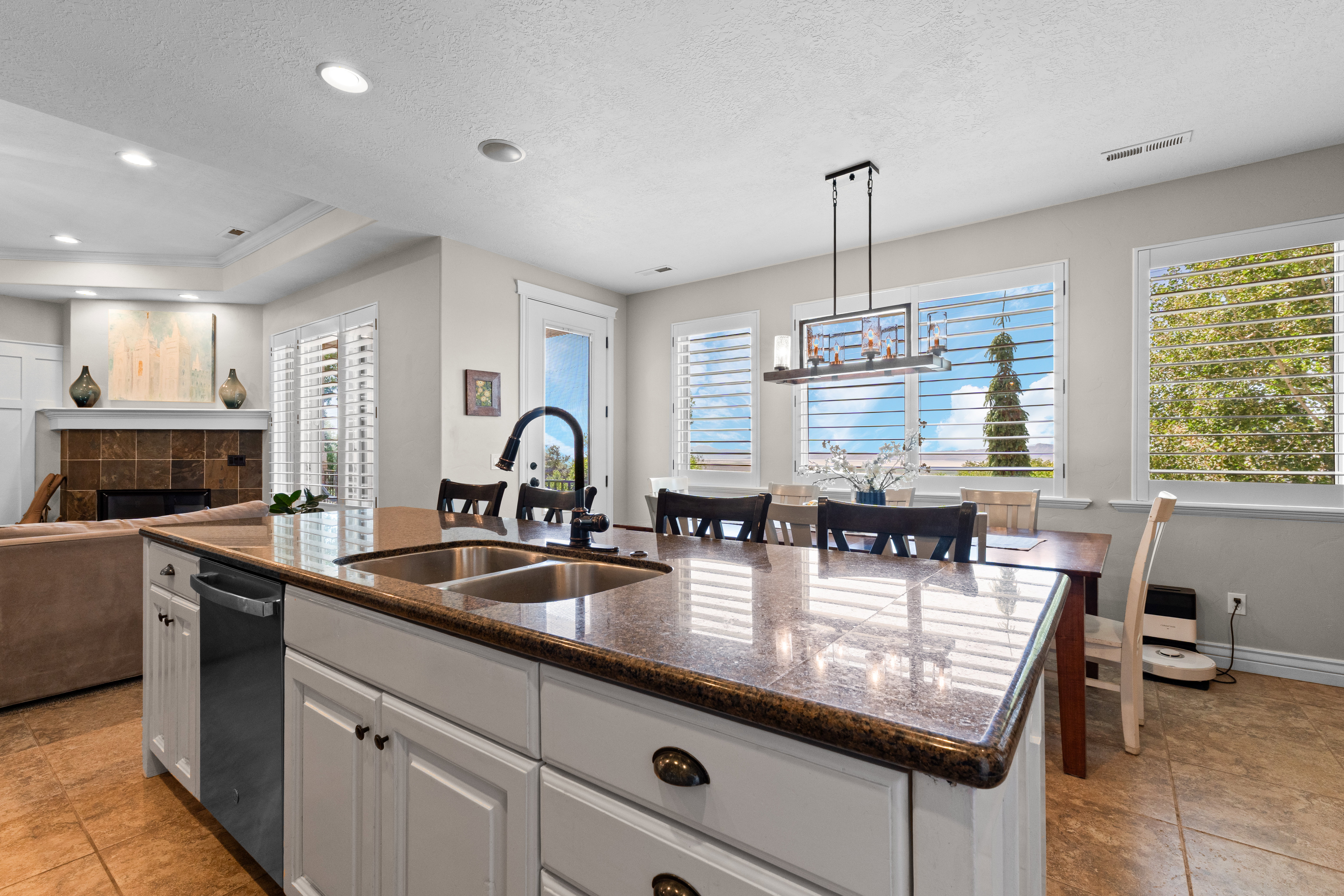 Spacious kitchen island featuring an undermount double sink with a gooseneck faucet, light-colored cabinetry, and a built-in dishwasher