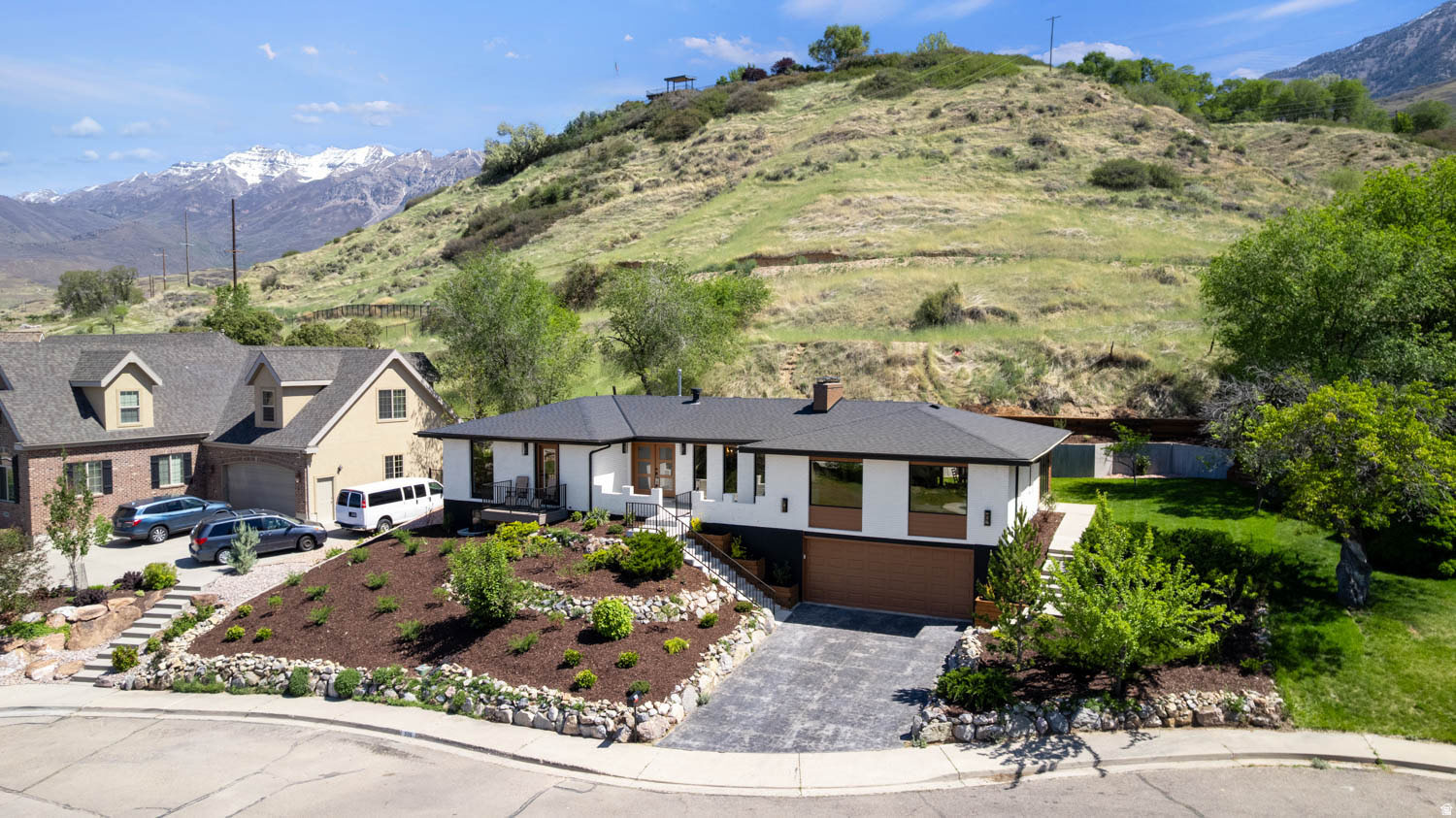 Contemporary residence featuring a dark roof, white siding, and wood-finish garage door