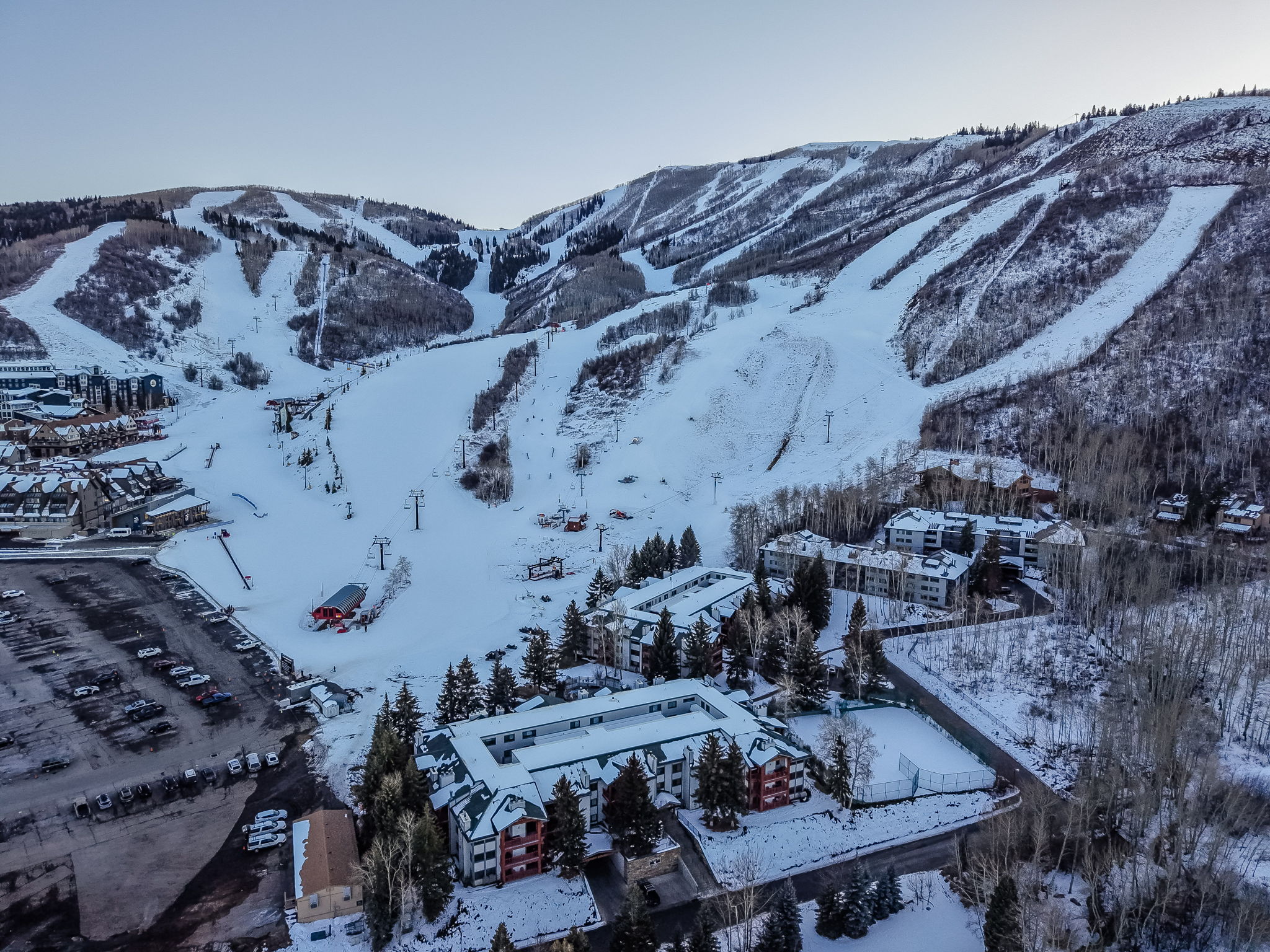 Aerial perspective showcasing multiple properties nestled at the base of a snow-covered mountain with defined ski runs