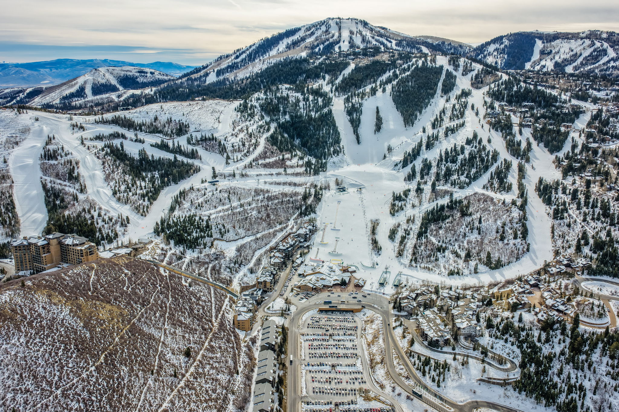 Snow-covered mountain landscape featuring ski slopes, evergreen trees, and a mountain base area