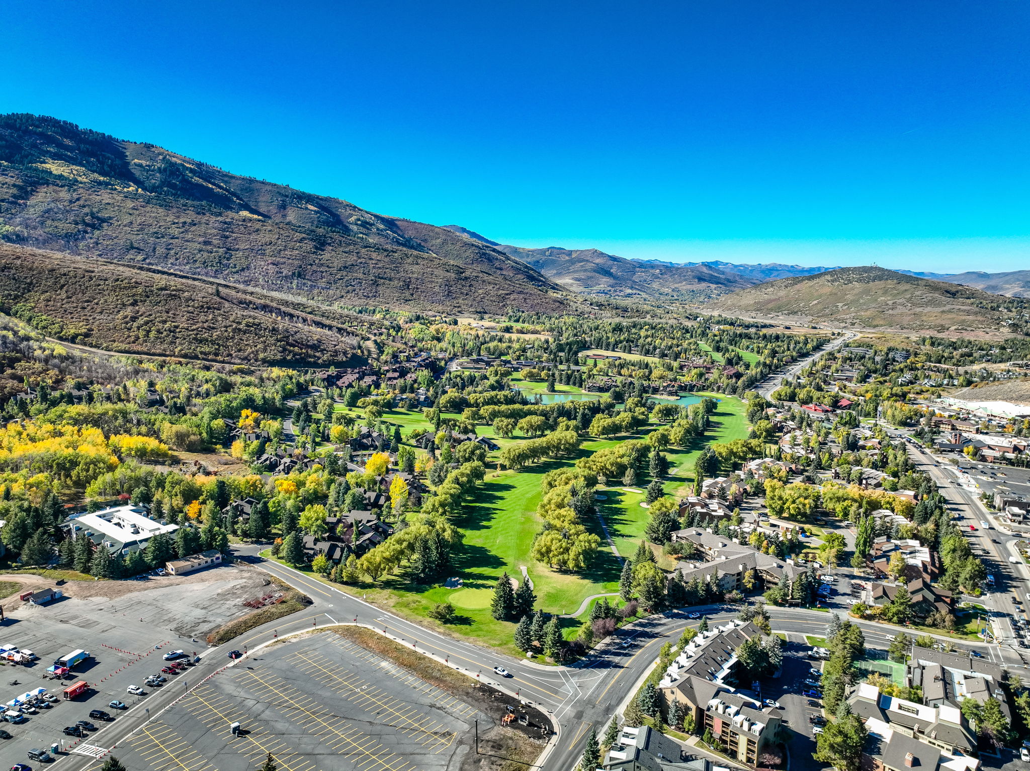 Expansive aerial perspective showcasing a mountainous terrain, a verdant golf course, and a residential area