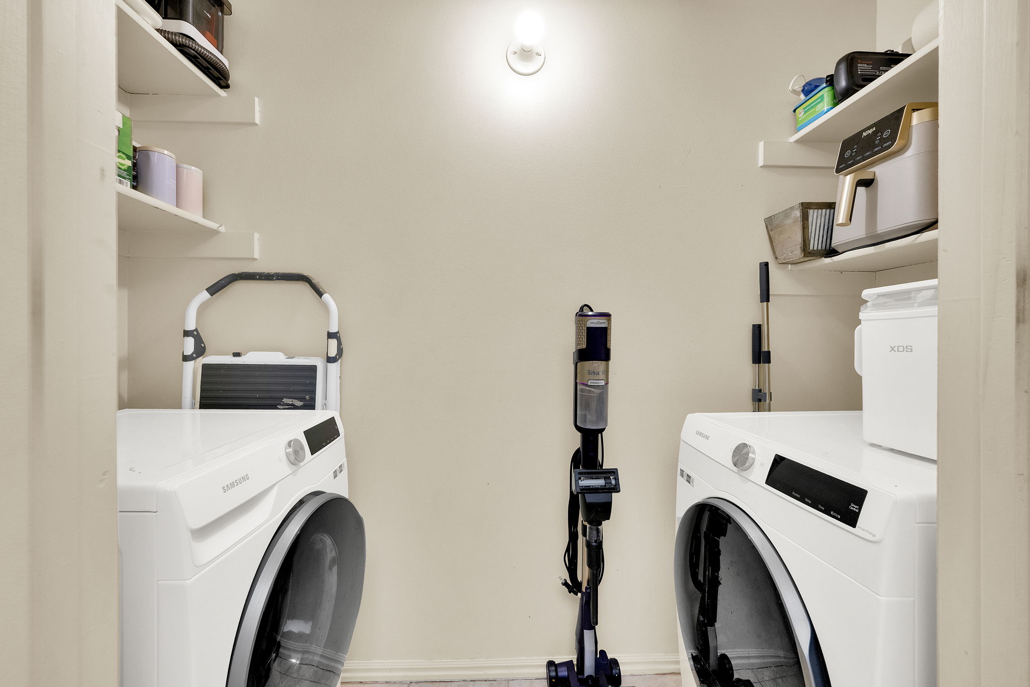 Dedicated utility area featuring built-in shelving, a wall-mounted light fixture, and light-toned wall paint