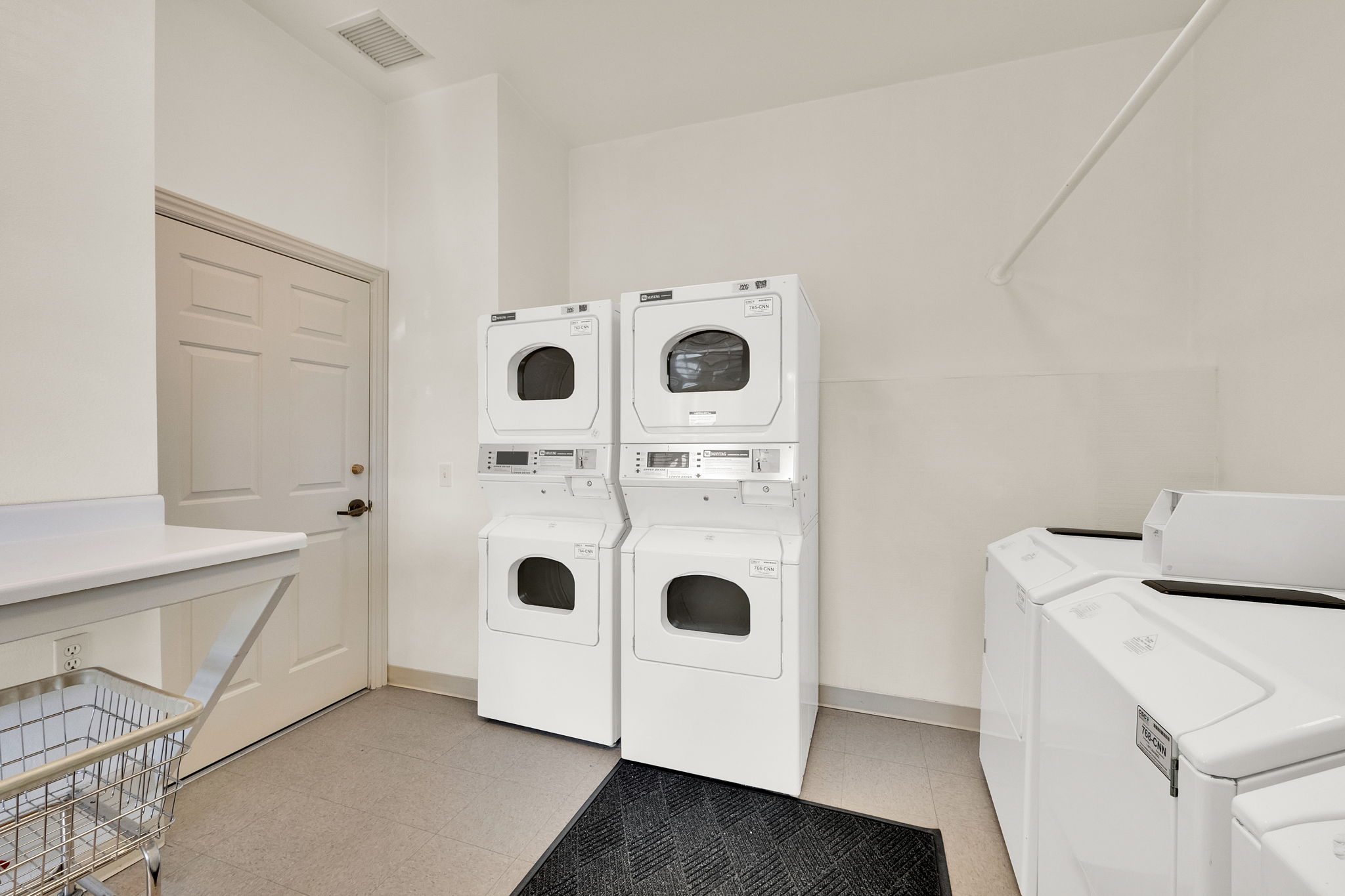 Dedicated laundry area featuring multiple stacked washer/dryer units and additional top-load washing machines