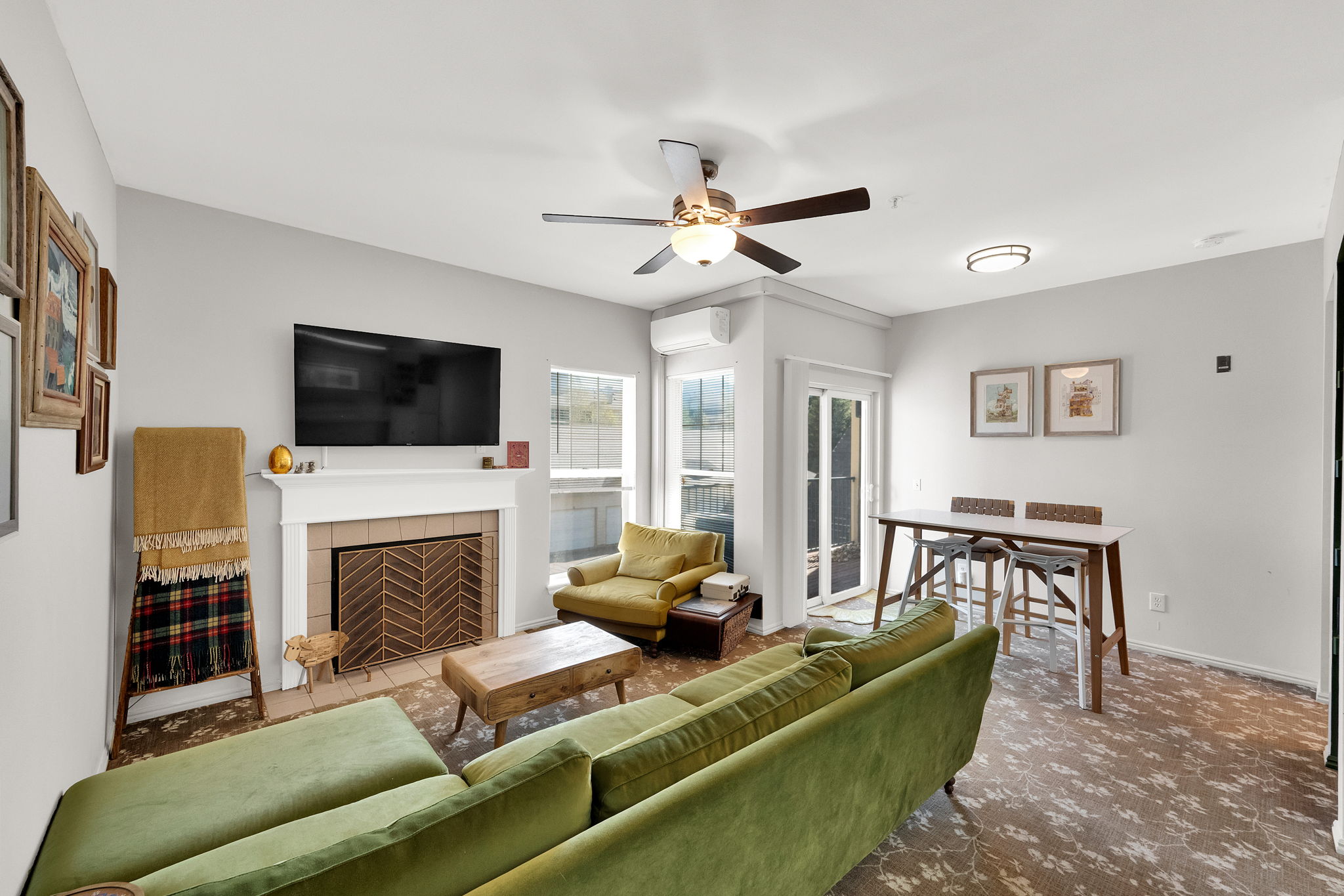 Living room featuring a fireplace with a decorative metal screen, wall-mounted television, and a ceiling fan with integrated lighting