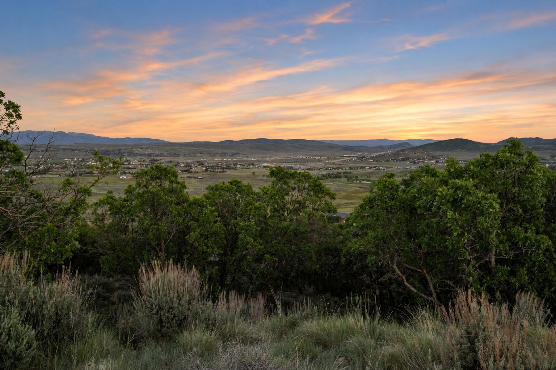 Expansive mountain backdrop with a vibrant sunset and natural desert flora