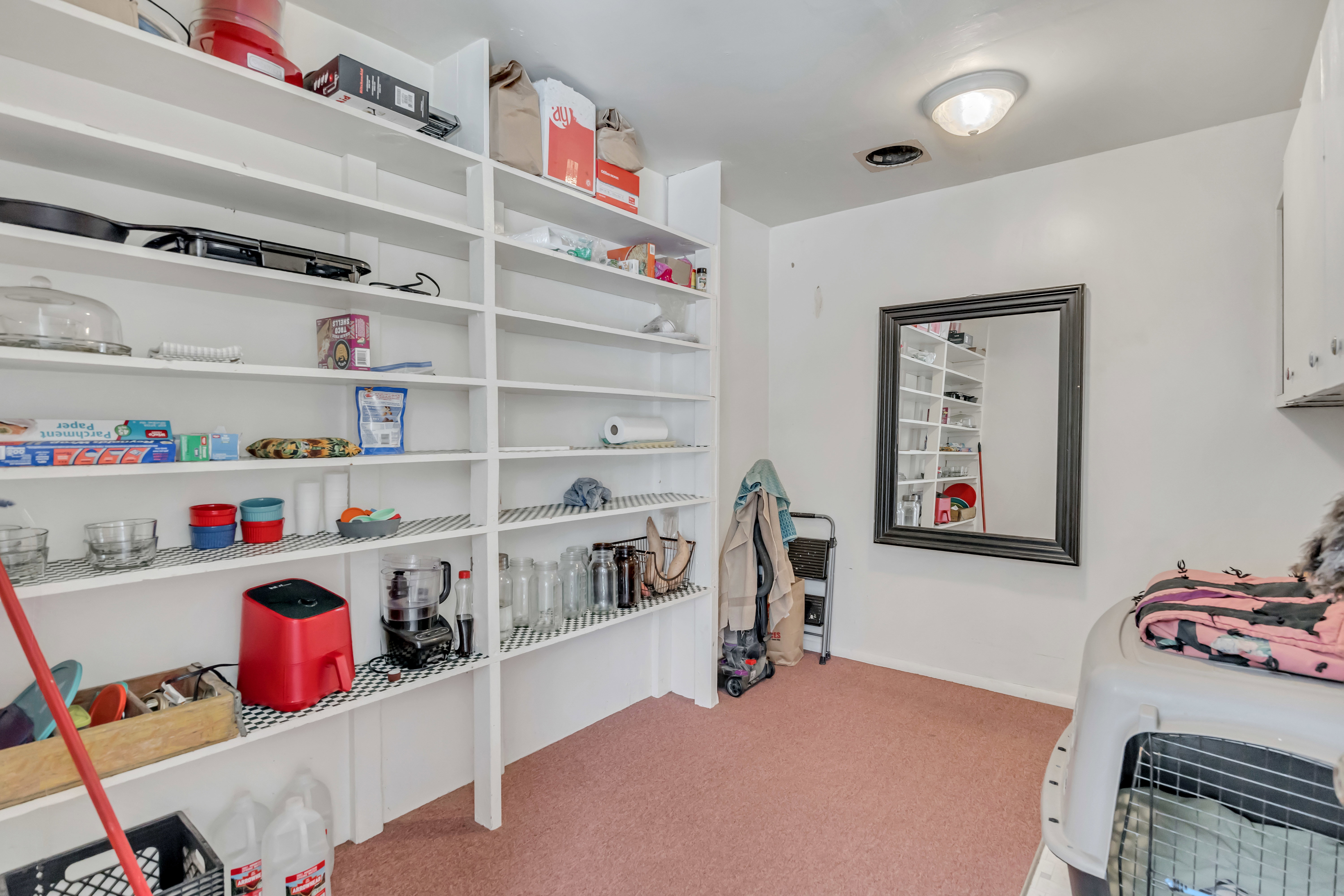 Utility room featuring extensive built-in shelving, white walls, and a ceiling-mounted light fixture