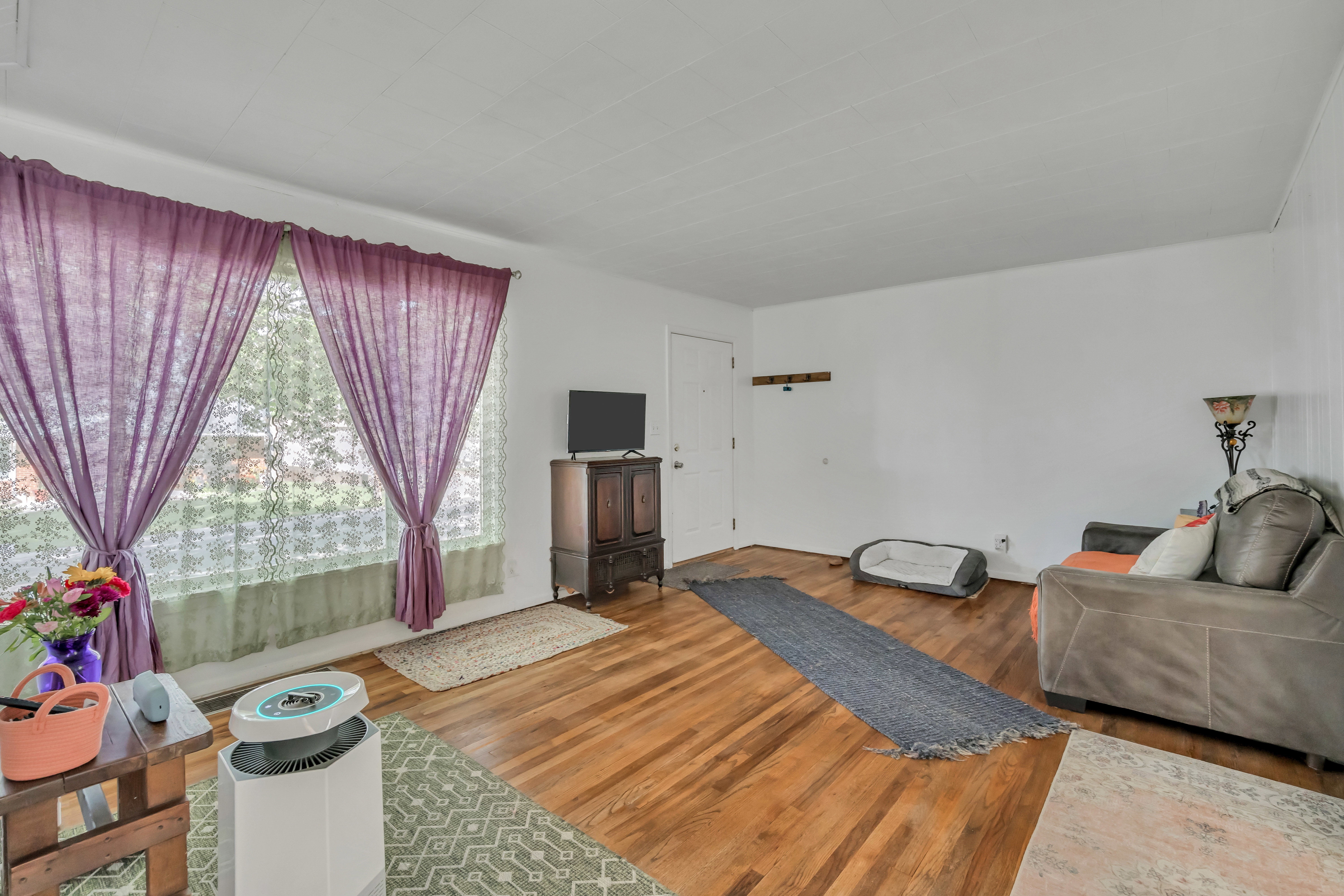 Living space featuring wood-finish flooring, white walls, and a prominent window
