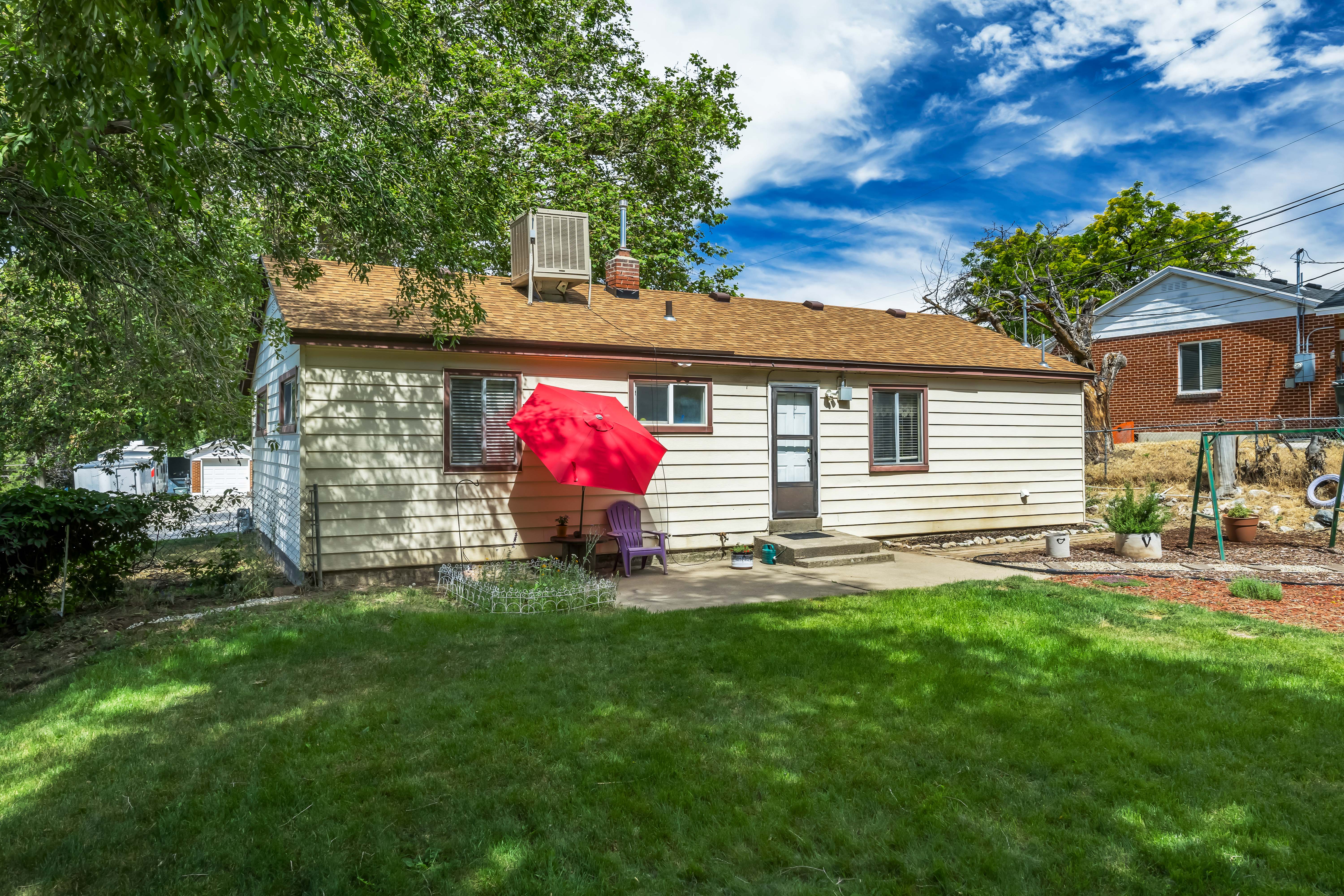 Rear exterior featuring neutral siding, a concrete patio, and a manicured lawn