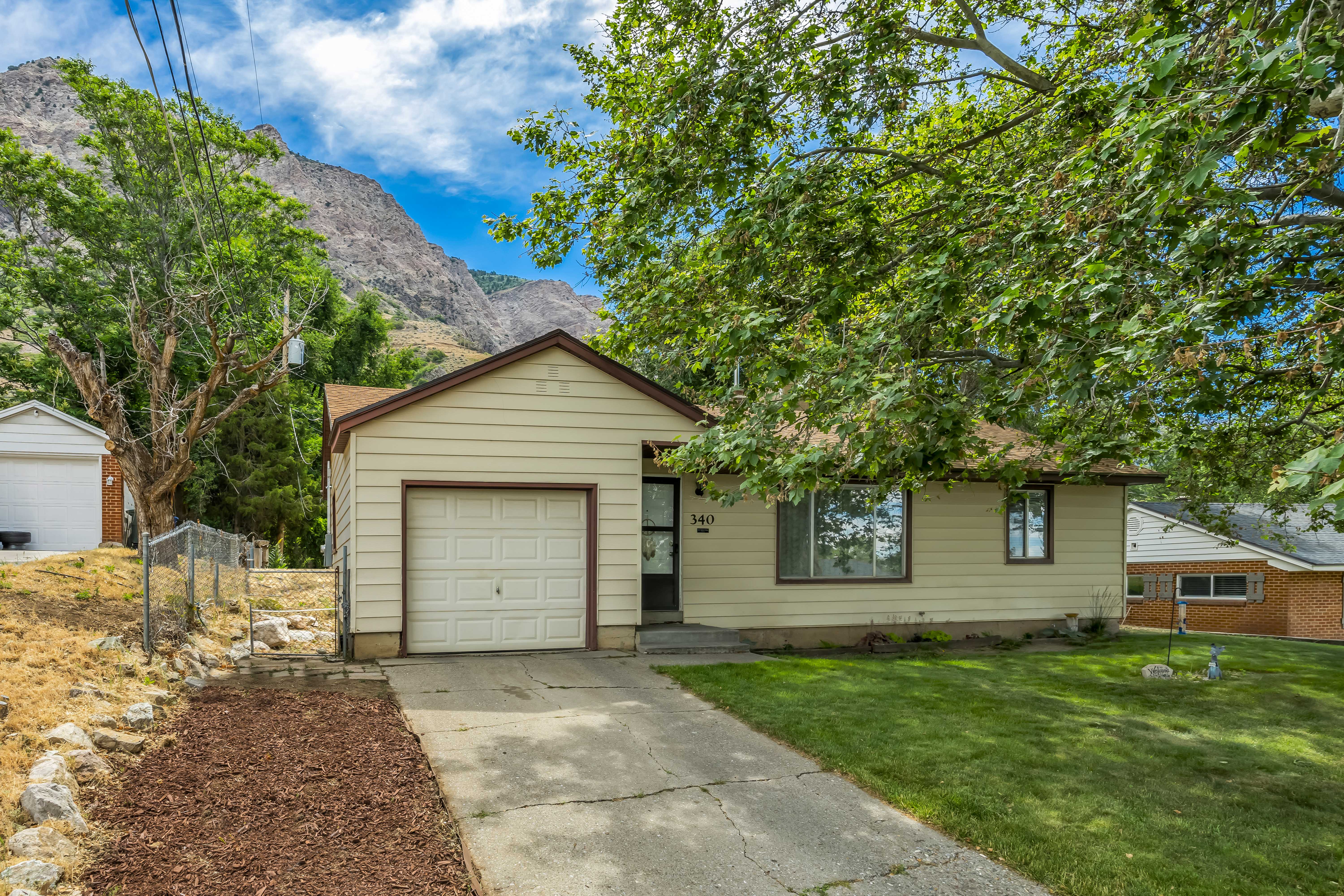 Single-level residence featuring a light-colored siding exterior, an attached single-car garage, and a concrete driveway